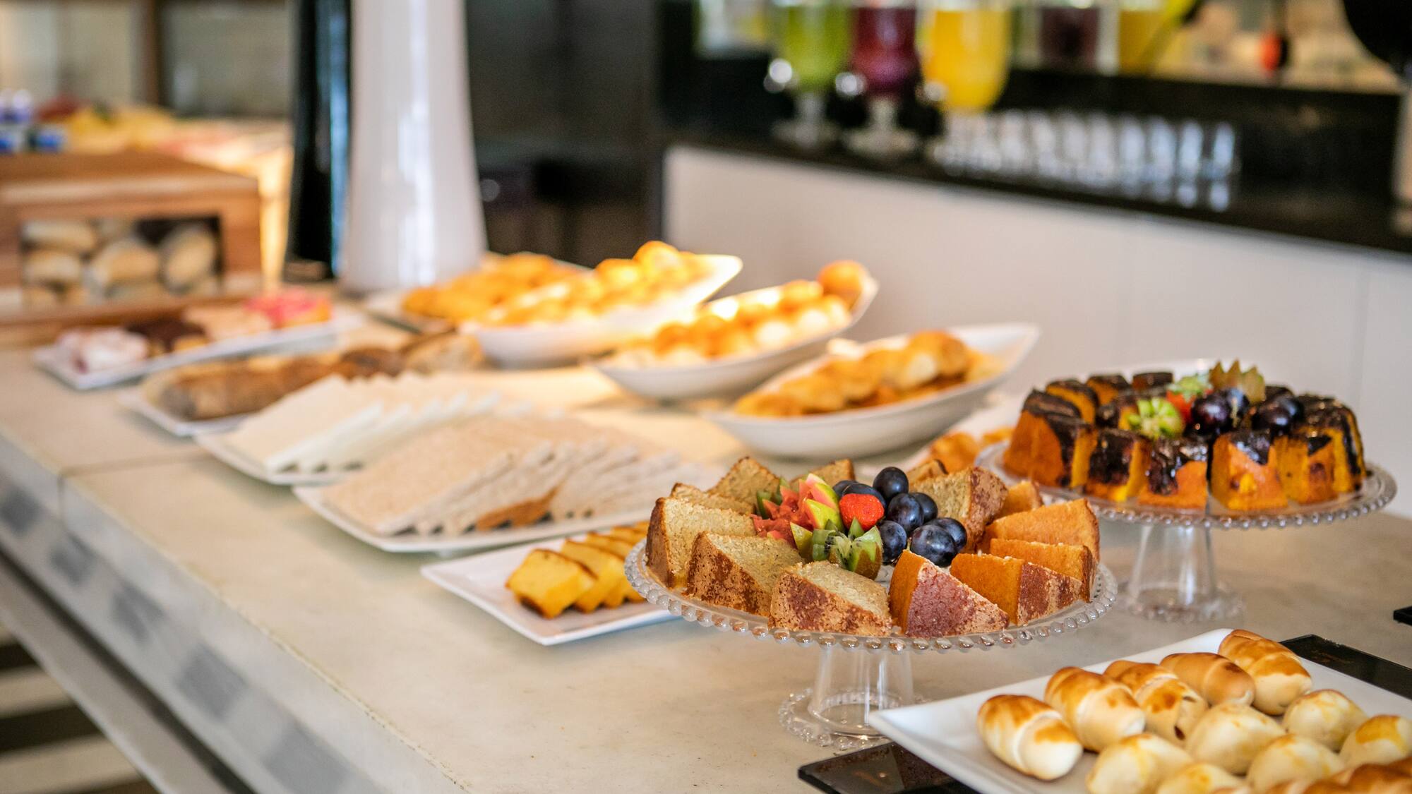 Hotel breakfast buffet featuring cakes, pastries, sandwiches, and fresh fruit.