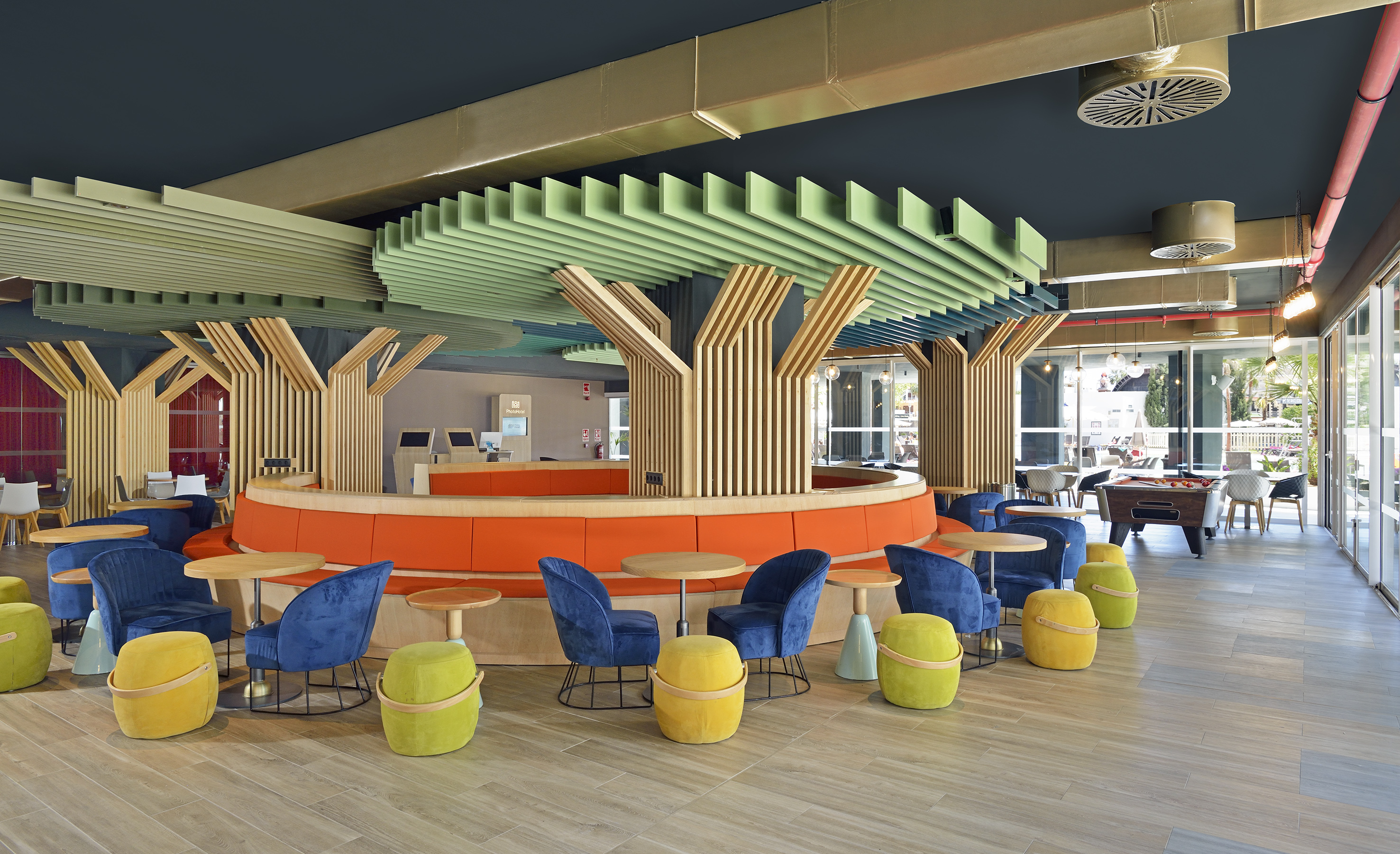 Modern lounge with tree-like decor, colorful seating, and circular sofa.