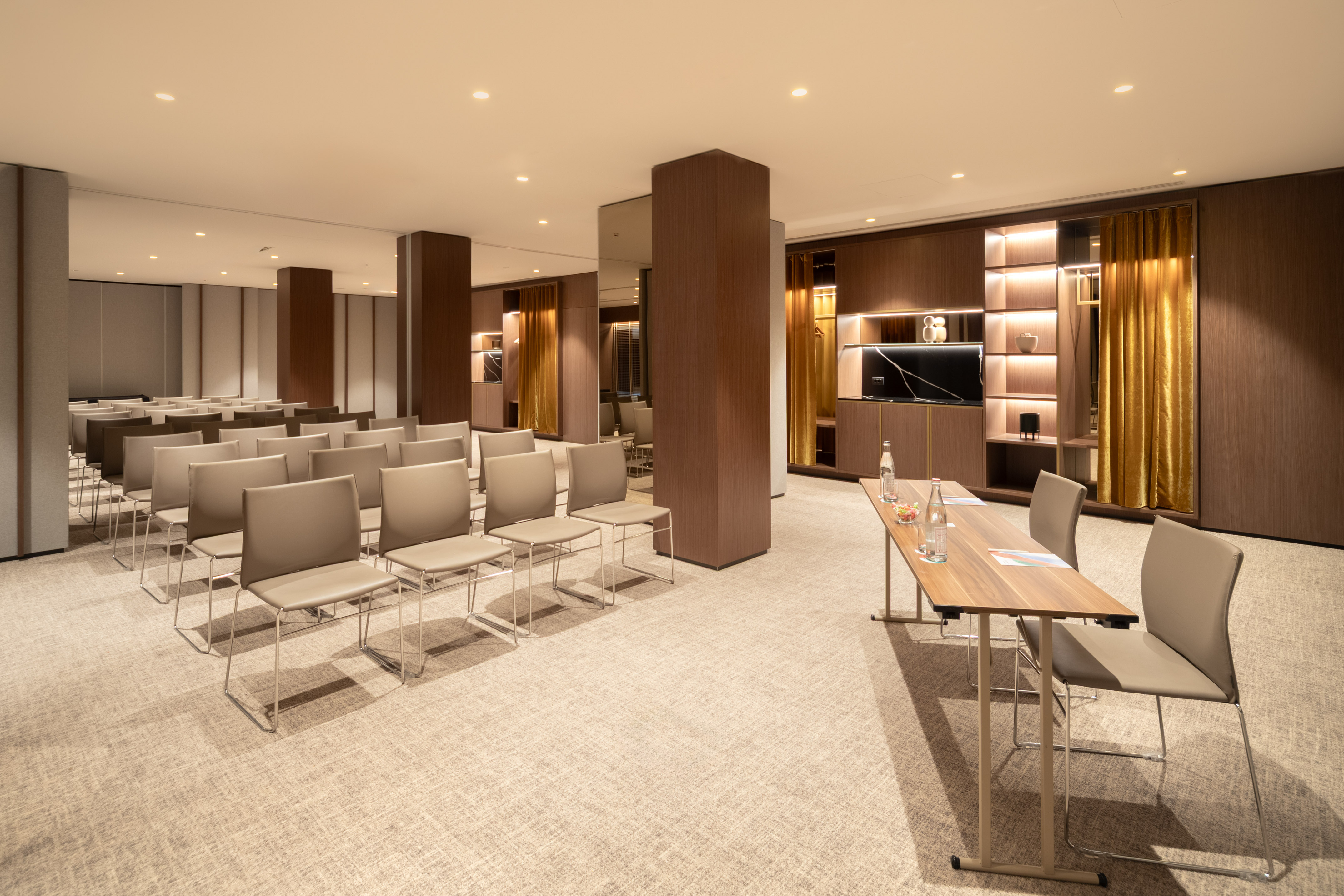 Spacious modern meeting room with rows of chairs and a presentation table.