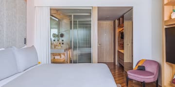 a bedroom with a bed and a pink chair