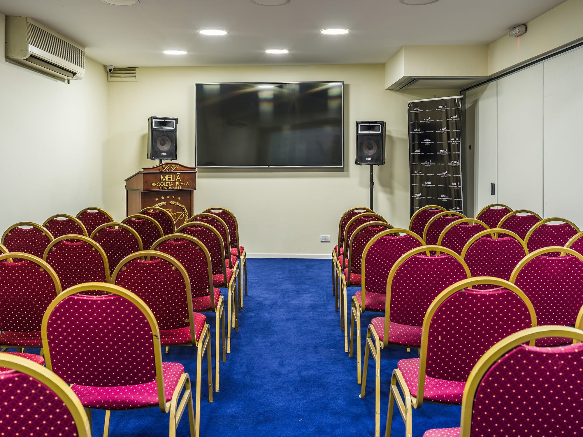 a room with red chairs and a screen