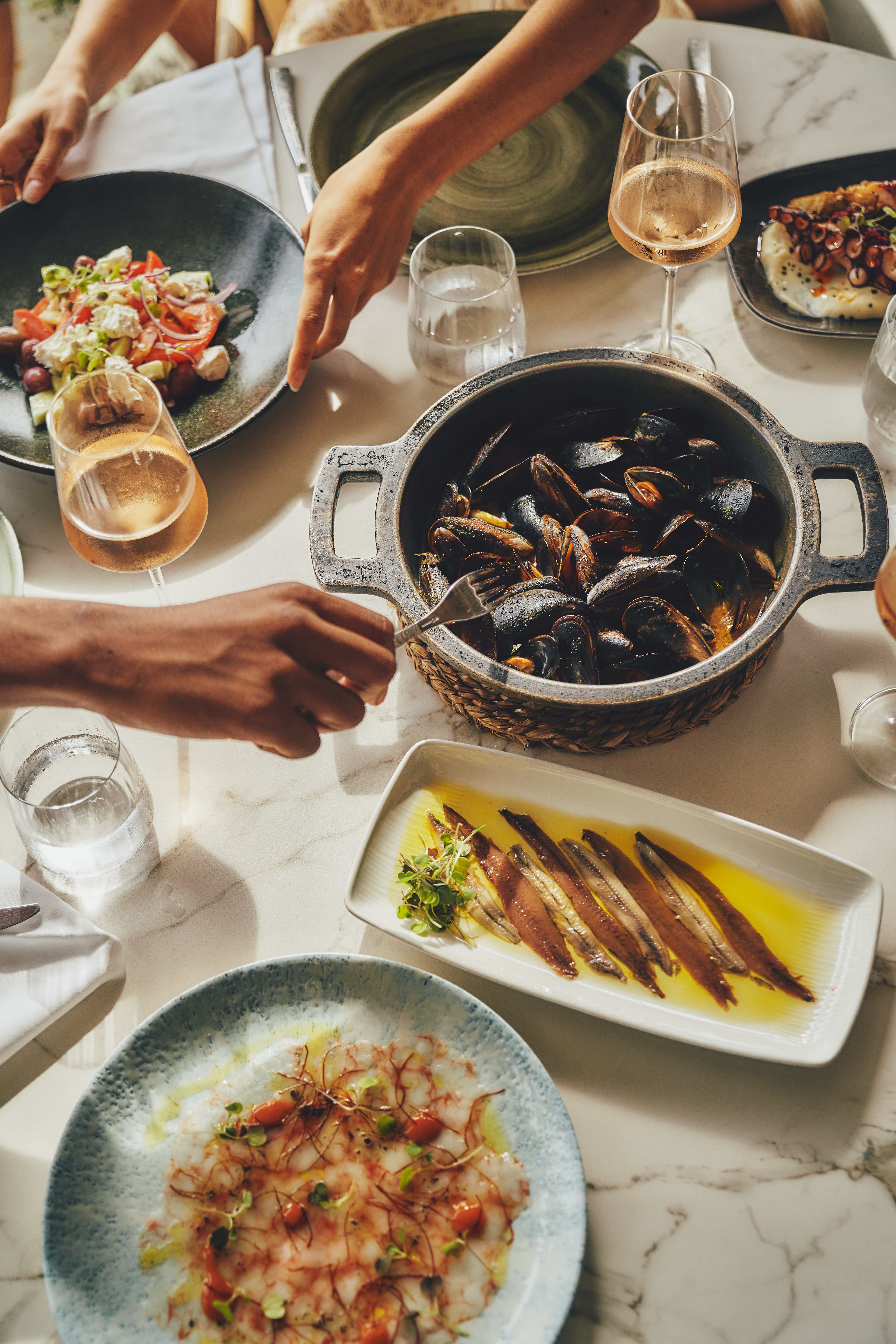 Mediterranean seafood table: mussels, Greek salad, anchovies, and wine.