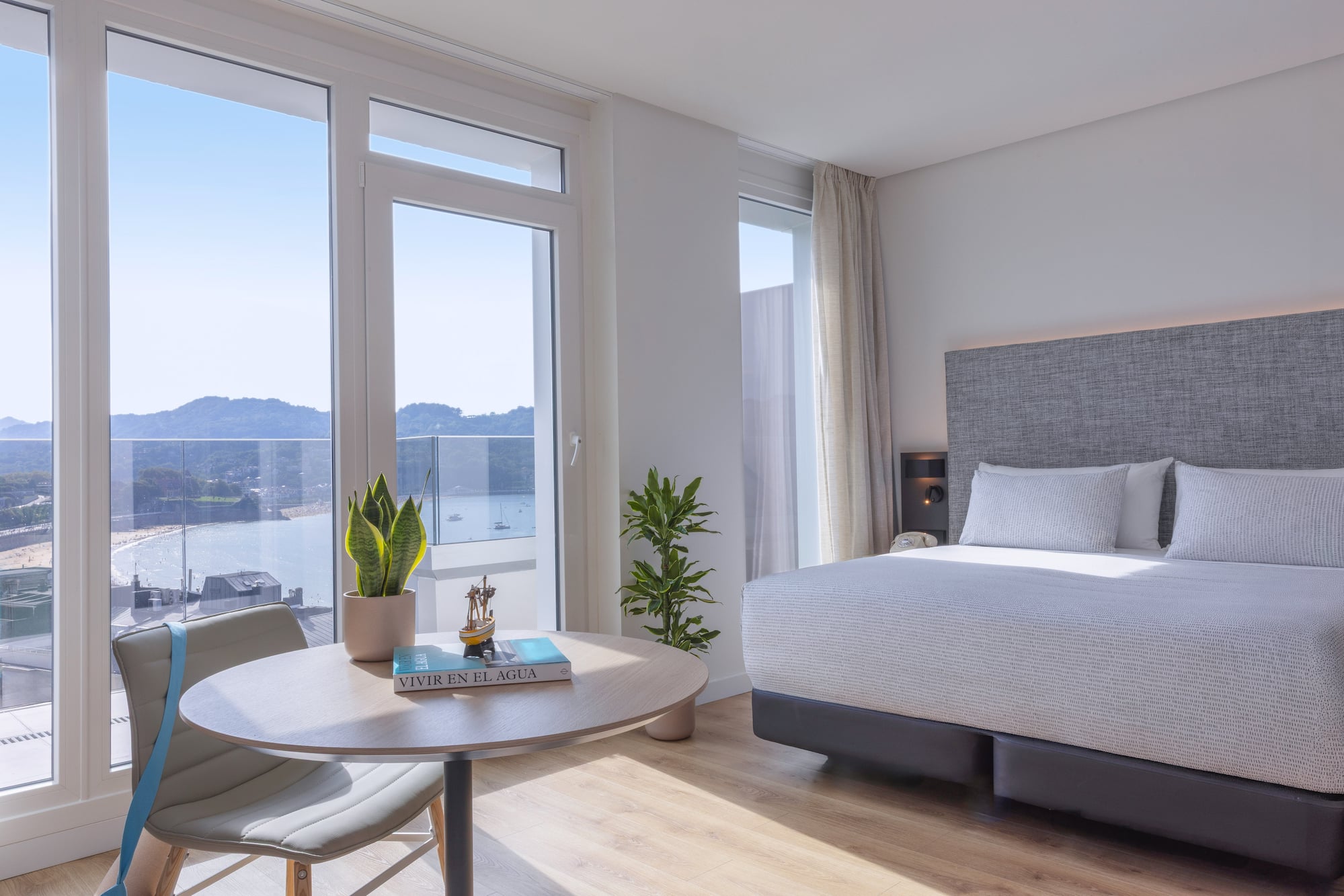 Habitación de hotel moderna con vista panorámica a la bahía y playa.