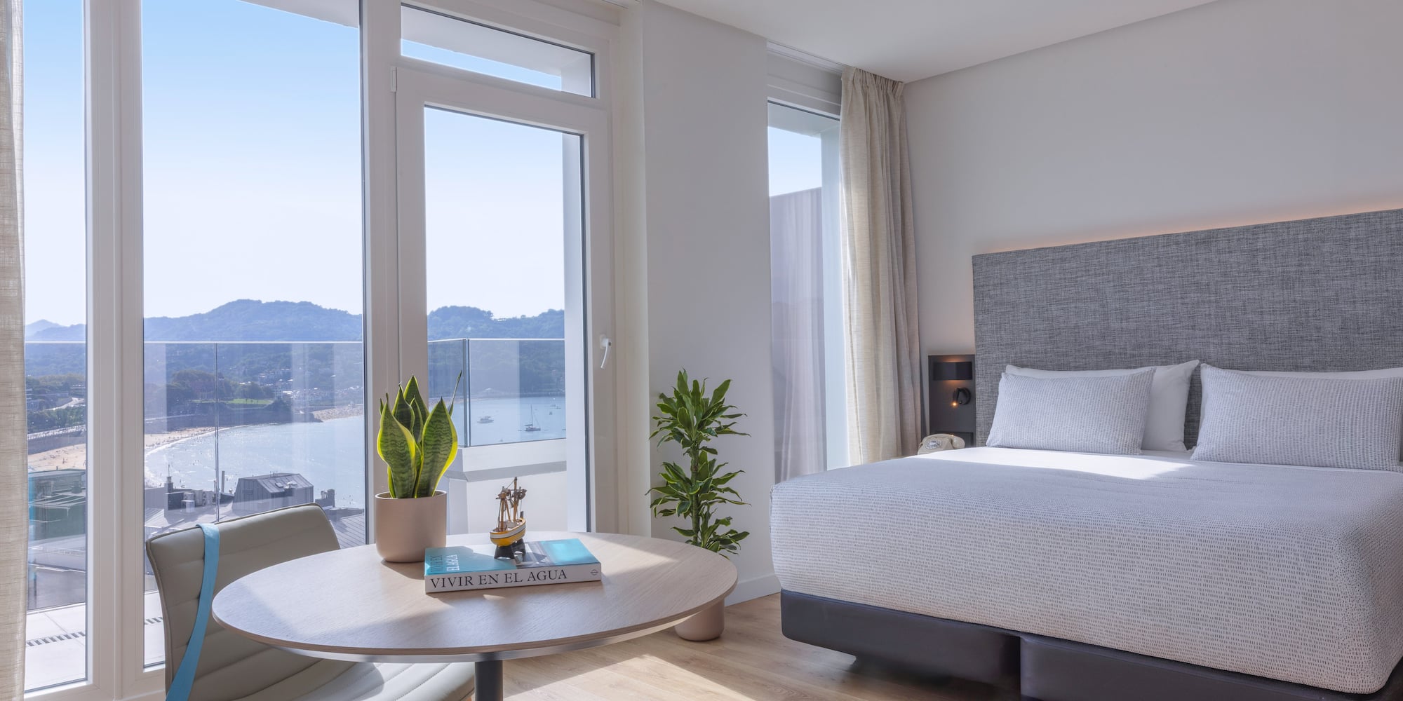 Habitación de hotel moderna con vista panorámica a la bahía y playa.