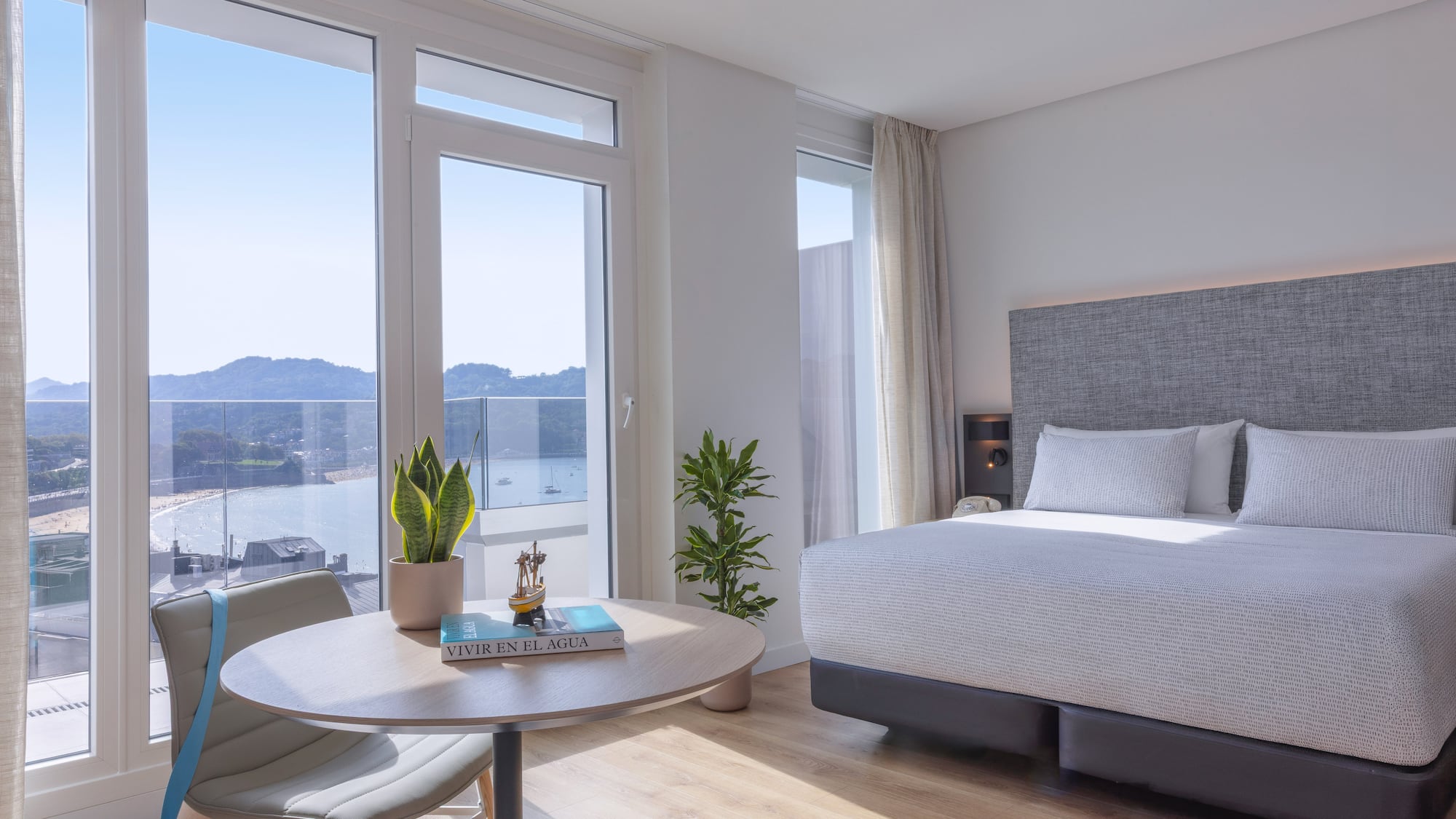 Habitación de hotel moderna con vista panorámica a la bahía y playa.