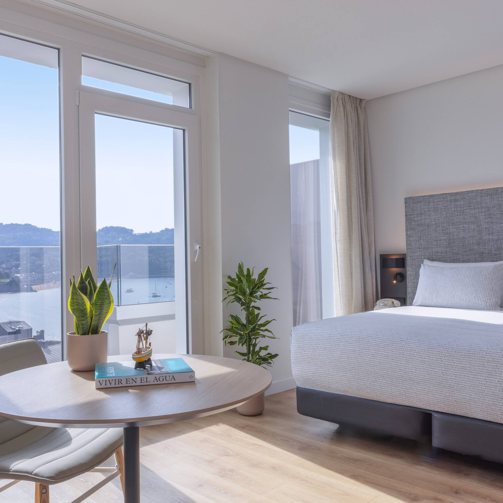 Habitación de hotel moderna con vista panorámica a la bahía y playa.
