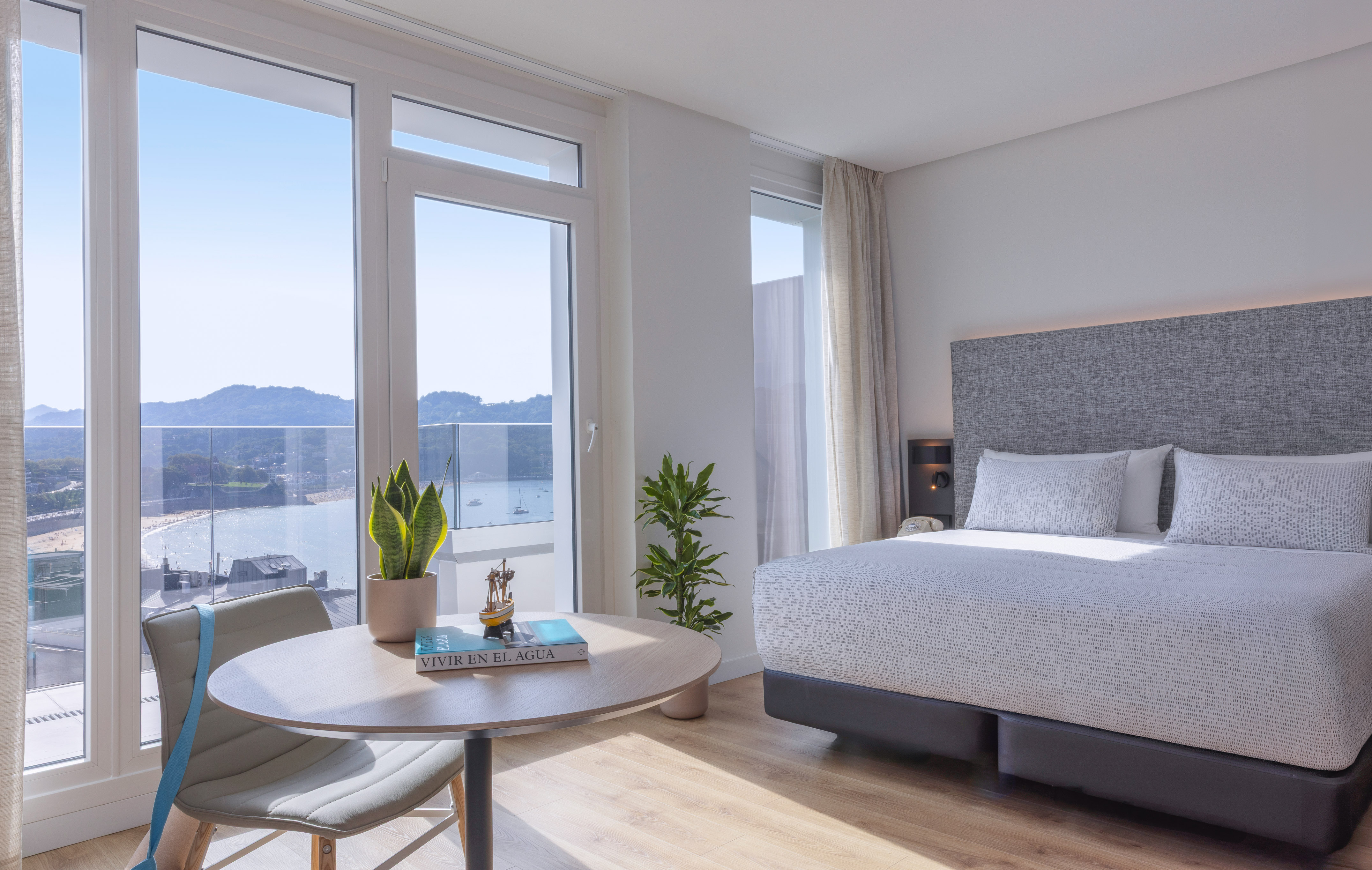 Habitación de hotel moderna con vista panorámica a la bahía y playa.