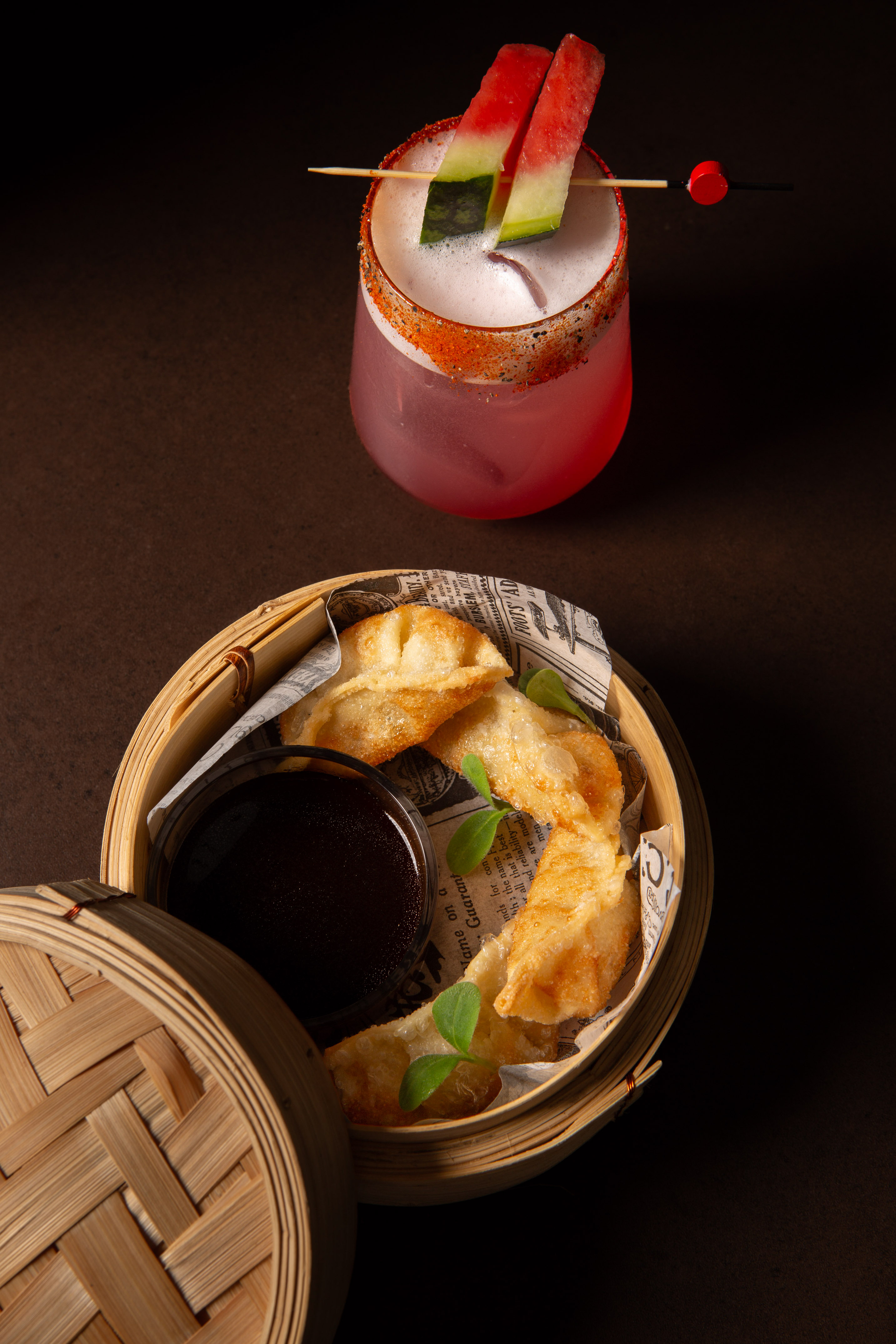 Watermelon cocktail with spicy rim and fried dumplings in bamboo steamer.