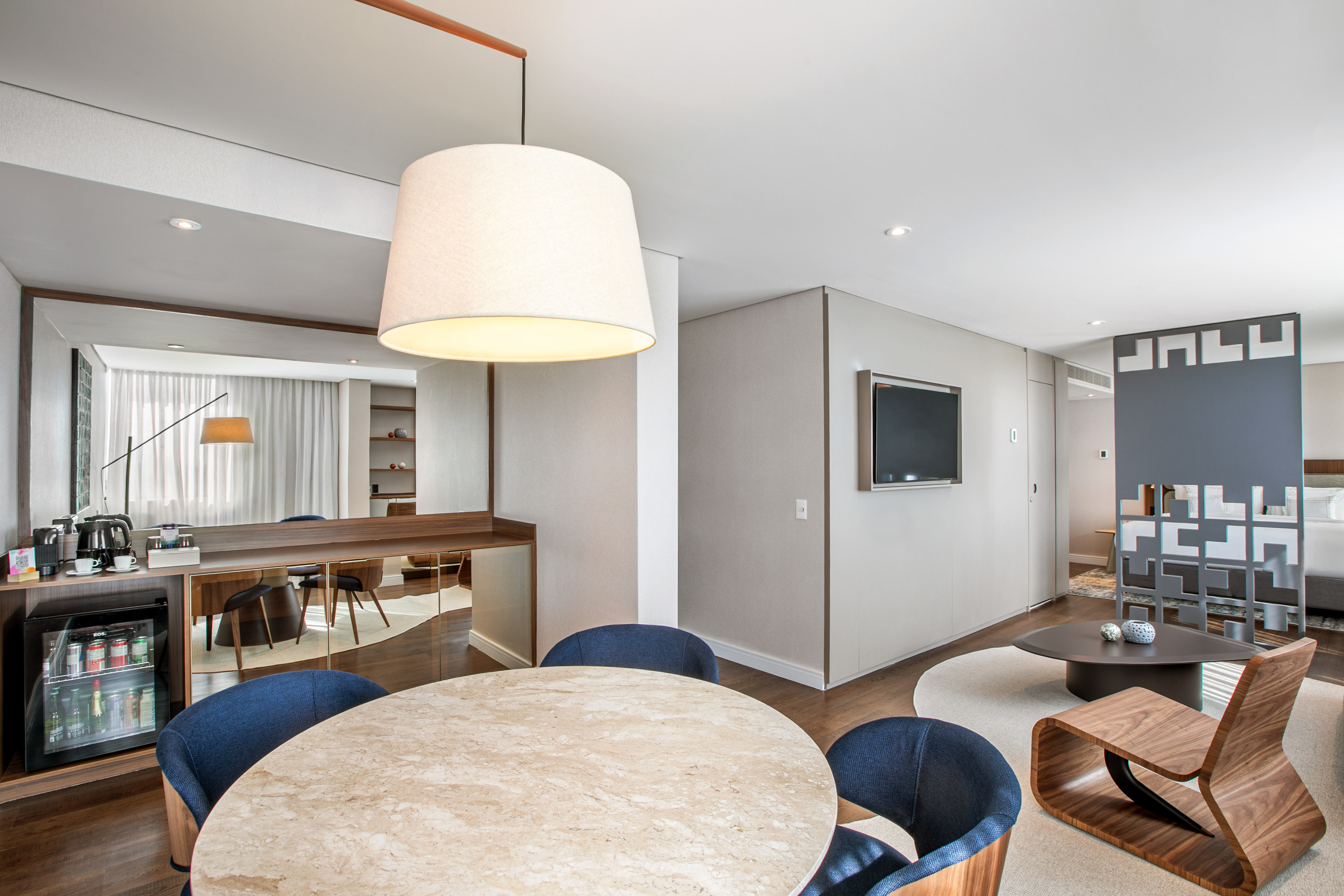 Modern hotel suite with dining area, mini-bar, and contemporary living room.
