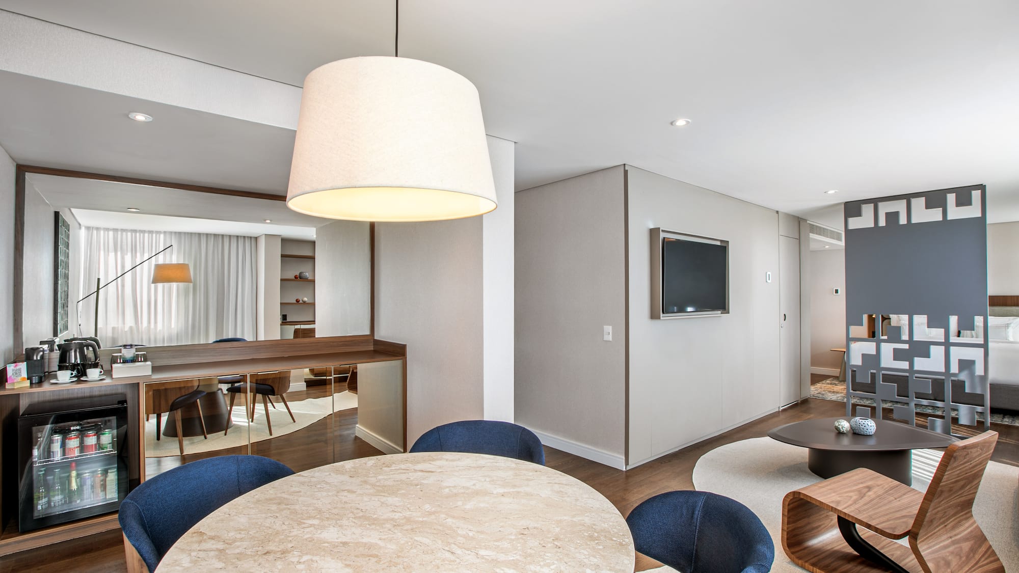 Modern hotel suite with dining area, mini-bar, and contemporary living room.
