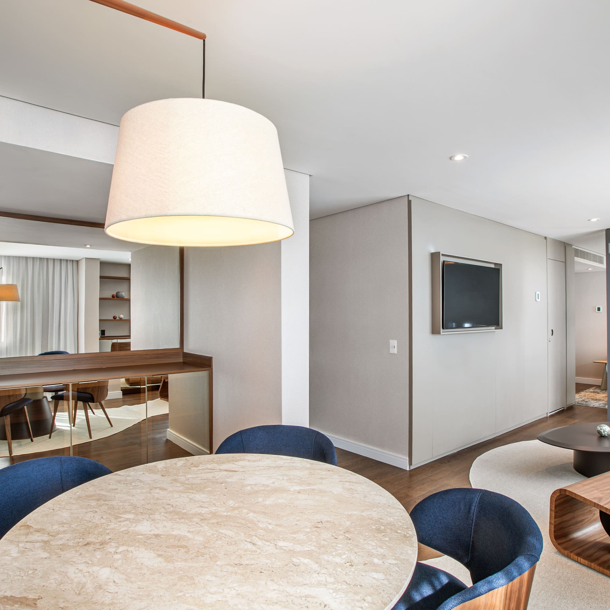 Modern hotel suite with dining area, mini-bar, and contemporary living room.