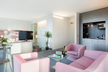 a living room with pink chairs and a television