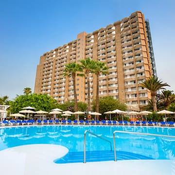 a large building with a pool and palm trees