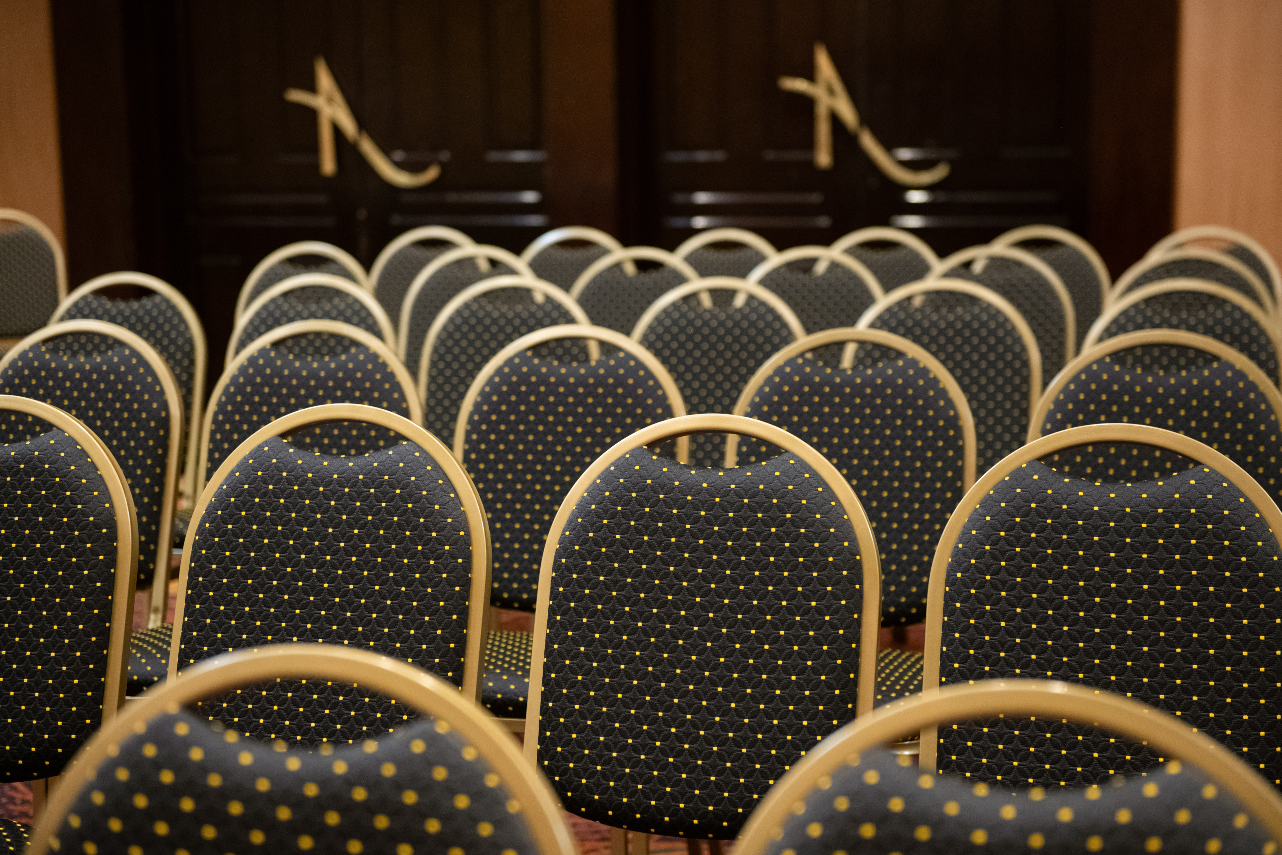 Empty black and gold banquet chairs in a conference room setup.