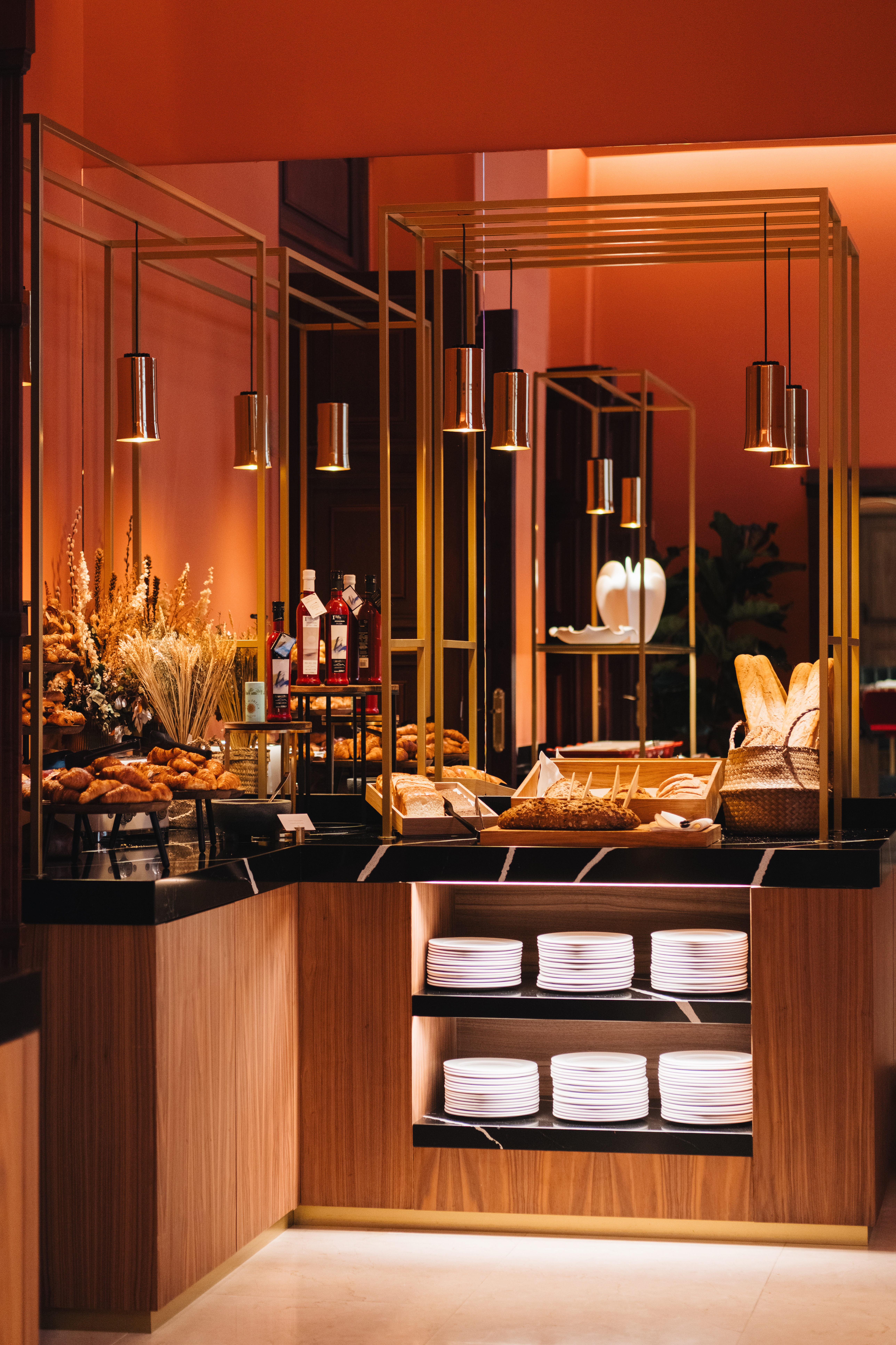 Luxury breakfast buffet with croissants, fresh bread, and modern pendant lights.
