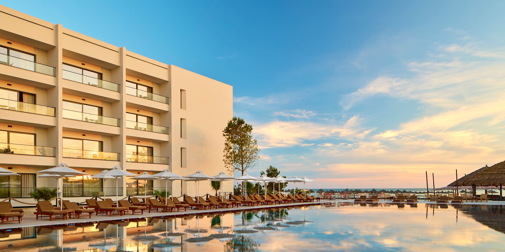 a pool with lounge chairs and umbrellas in front of a building