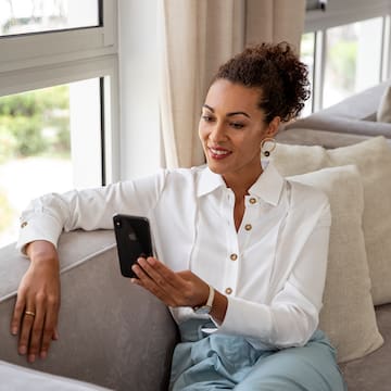 a woman sitting on a couch looking at a phone