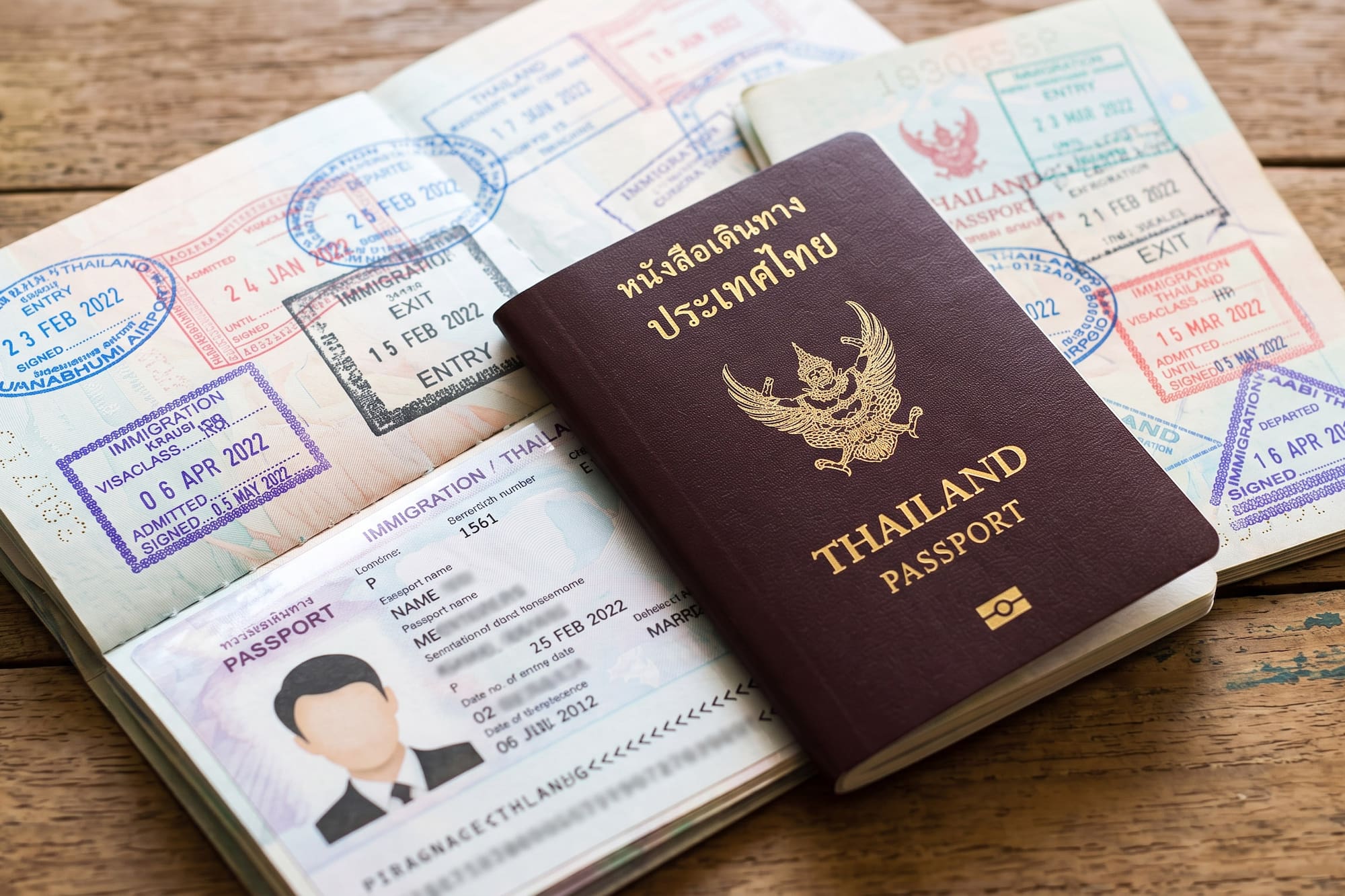 Thailand passport open to pages with multiple visa and immigration stamps.