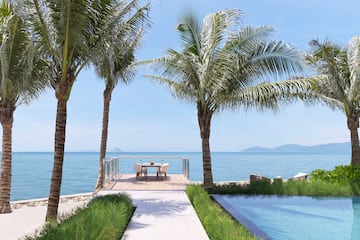 a deck with a table and chairs and a pool with palm trees
