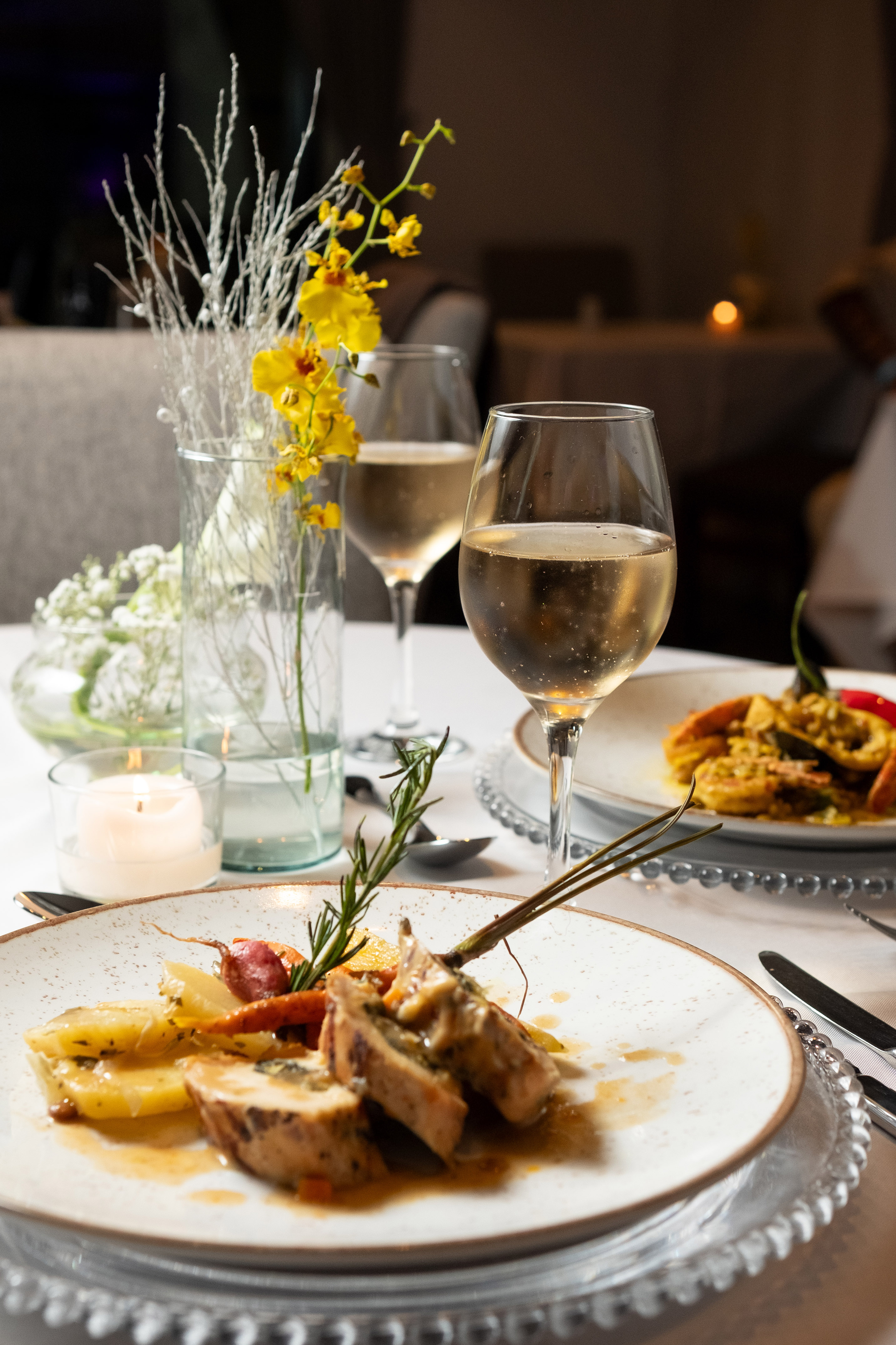 Gourmet chicken and roasted vegetables with sparkling wine at an elegant dinner.