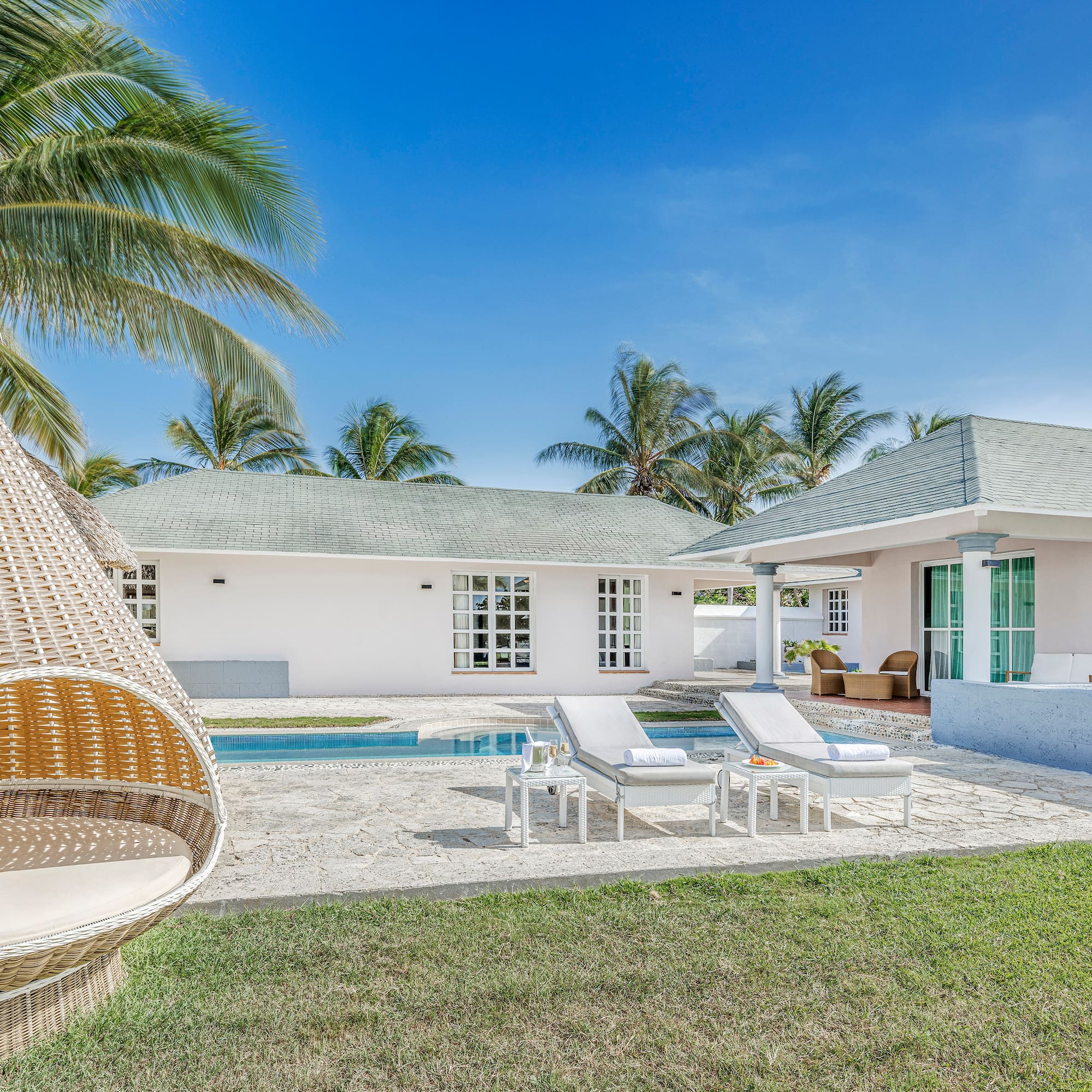 a white house with a pool and lounge chairs