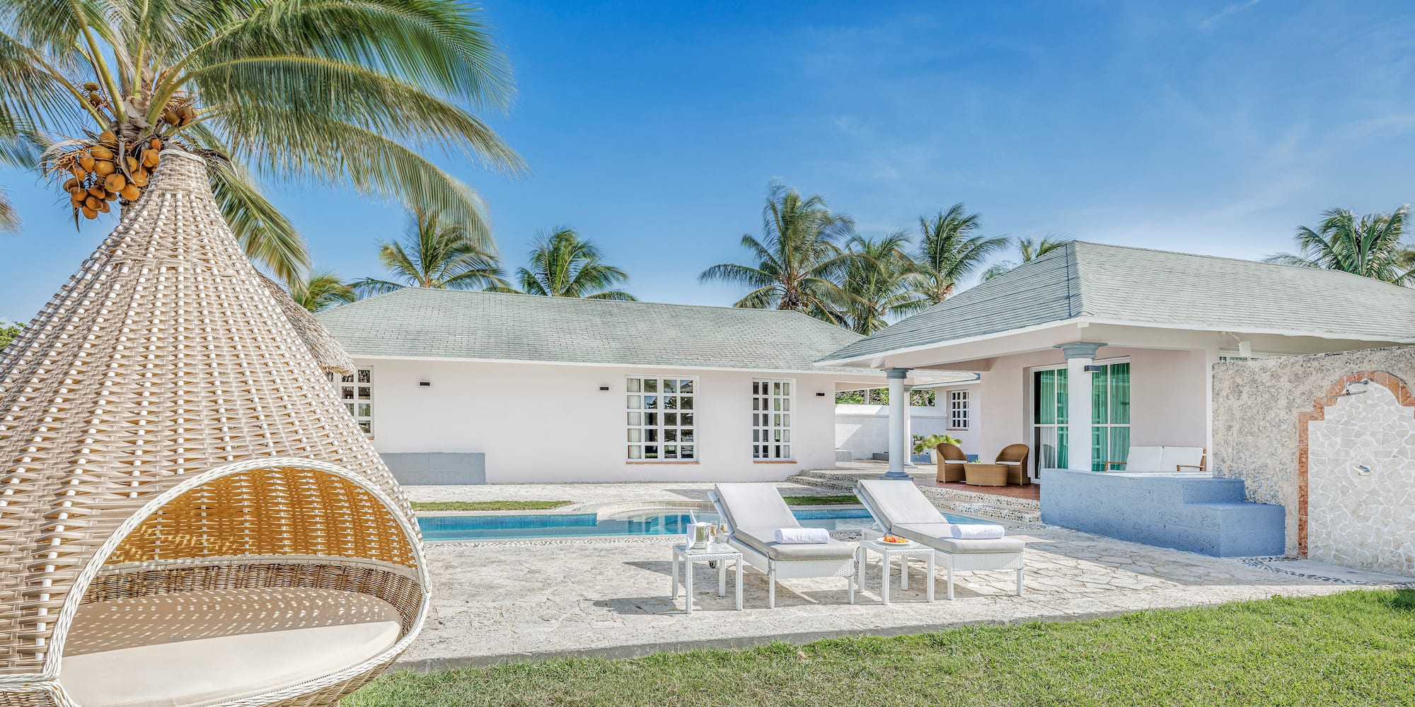 a white house with a pool and lounge chairs