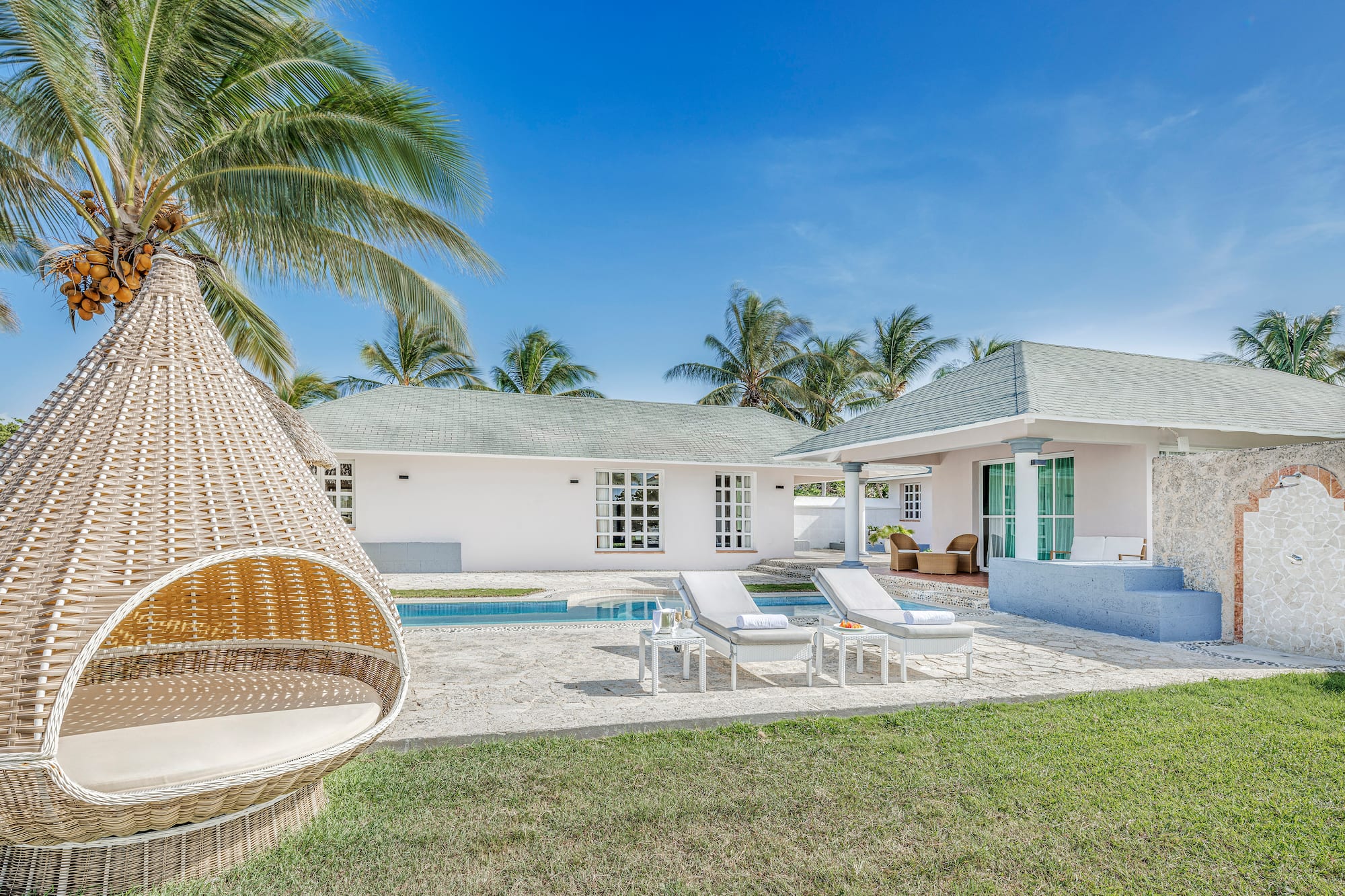 a white house with a pool and lounge chairs