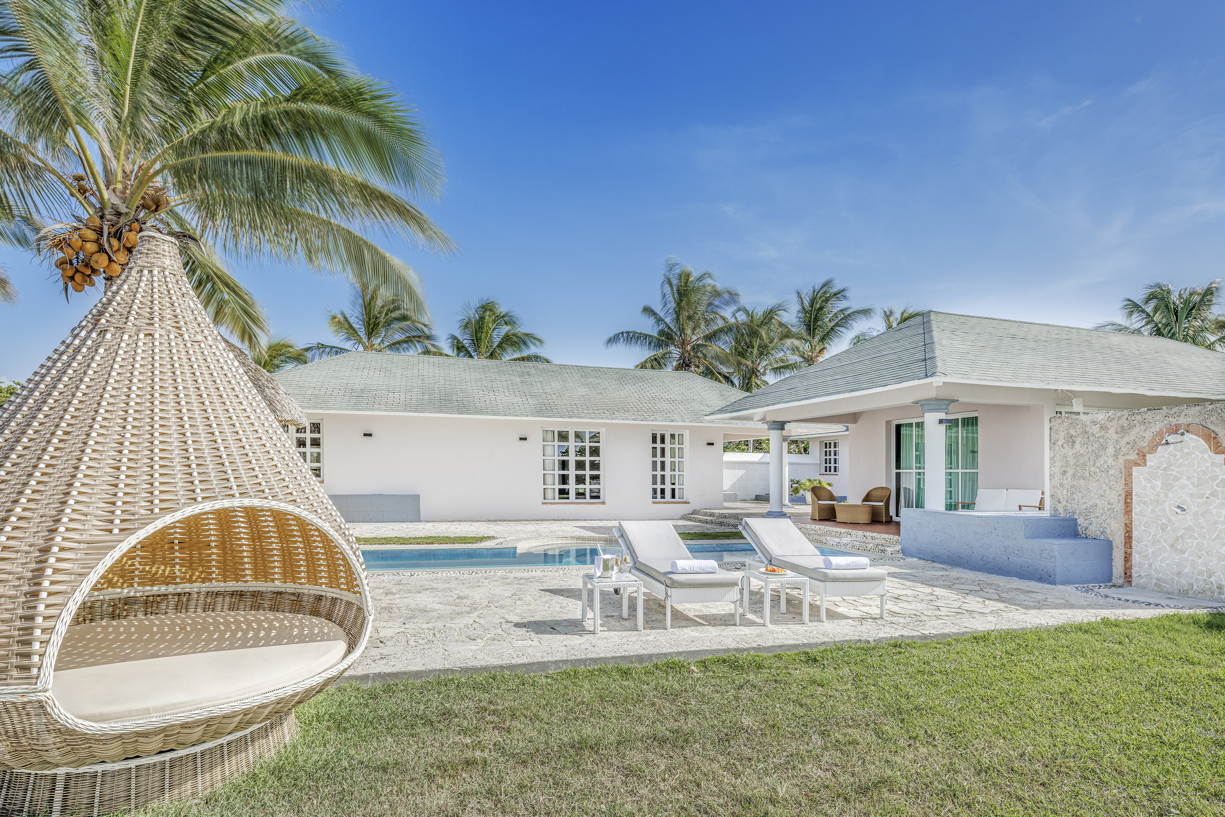 a white house with a pool and lounge chairs