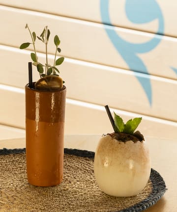 a brown cup with a plant in it and a white egg with straws