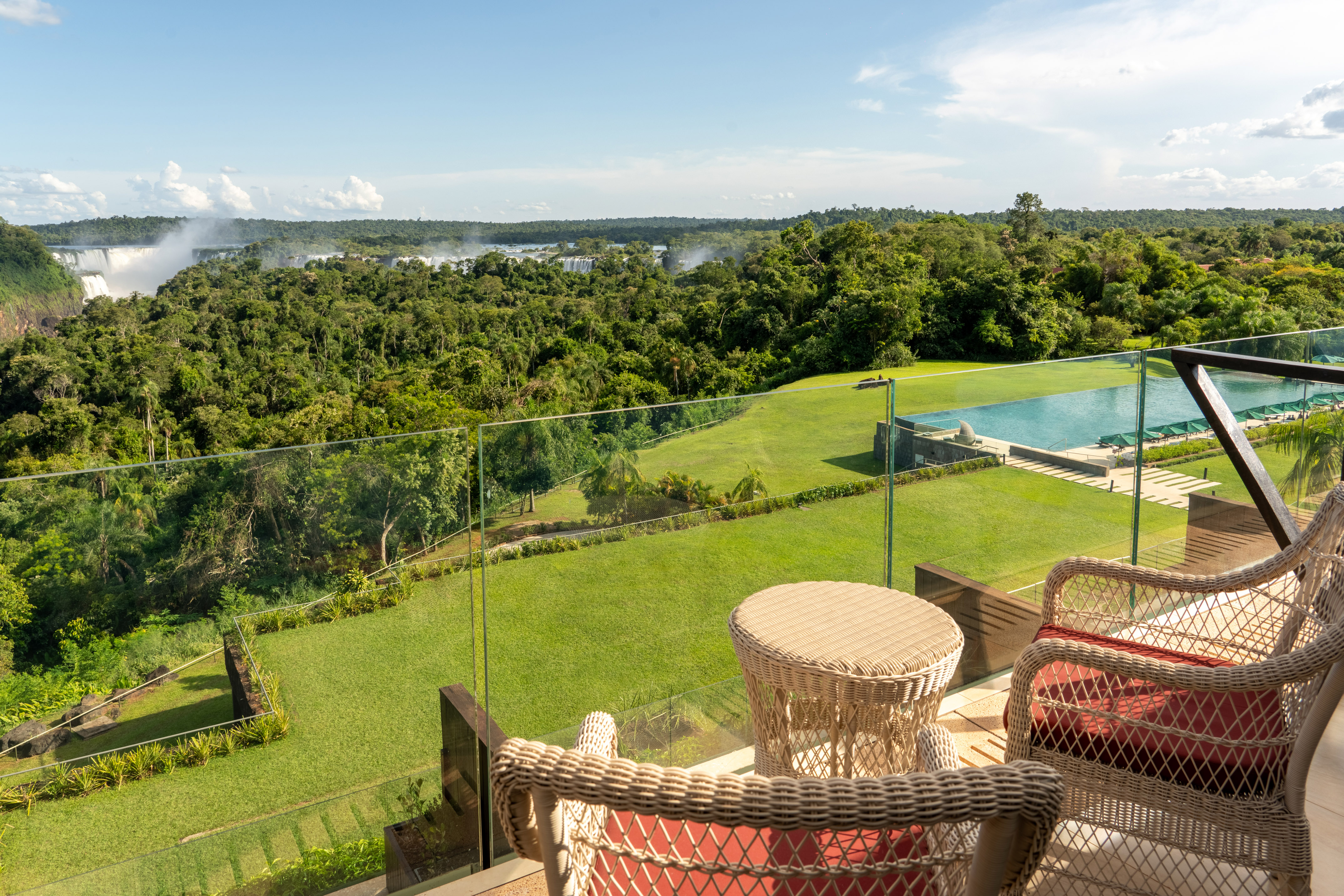 Balcony view of Iguazu Falls, lush rainforest, and resort infinity pool.