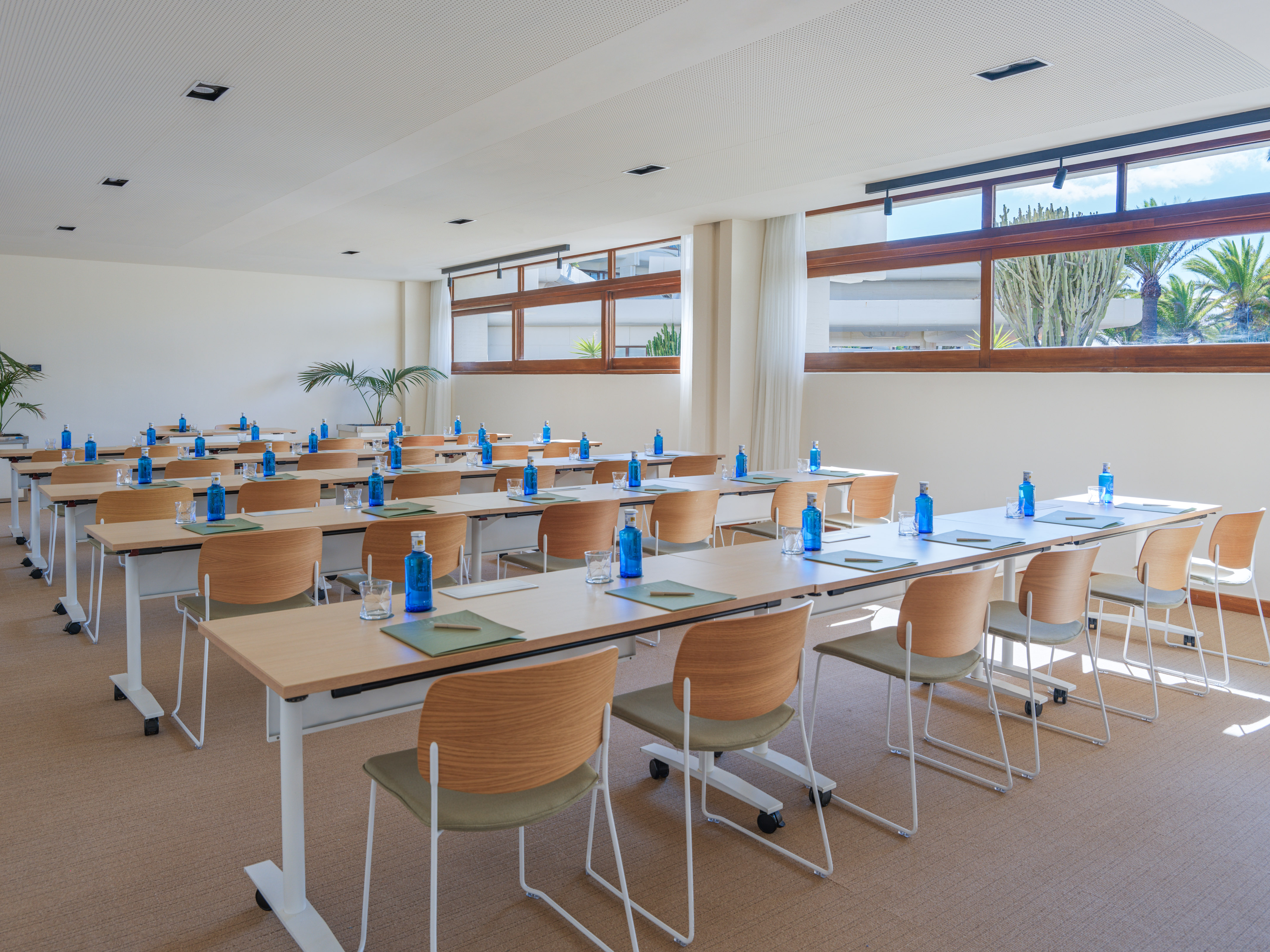 Modern conference room with tables, chairs, water bottles, and natural light.