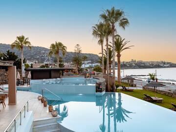 a pool with palm trees and a beach in the background