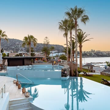 a pool with palm trees and a beach in the background