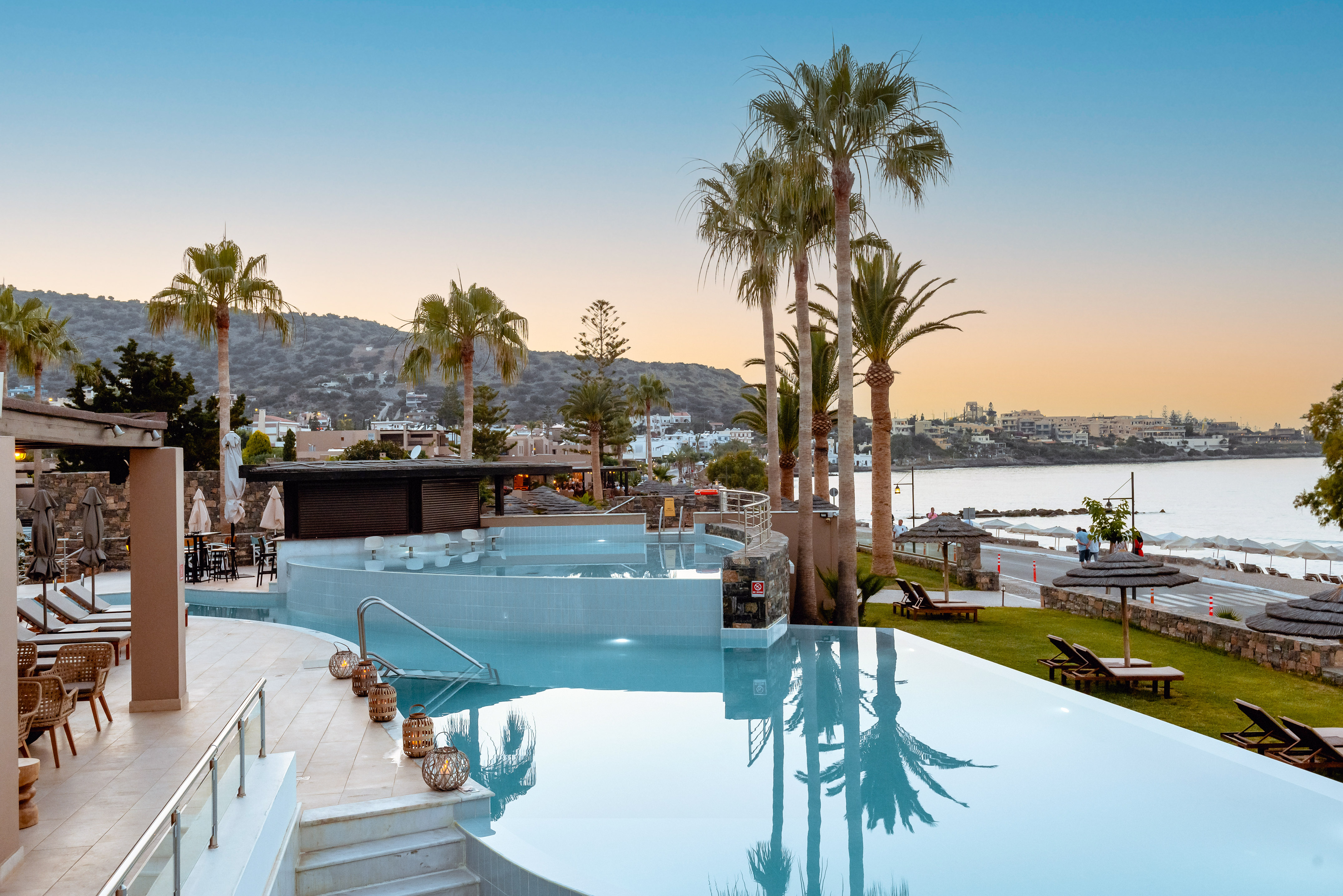 a pool with palm trees and a beach in the background