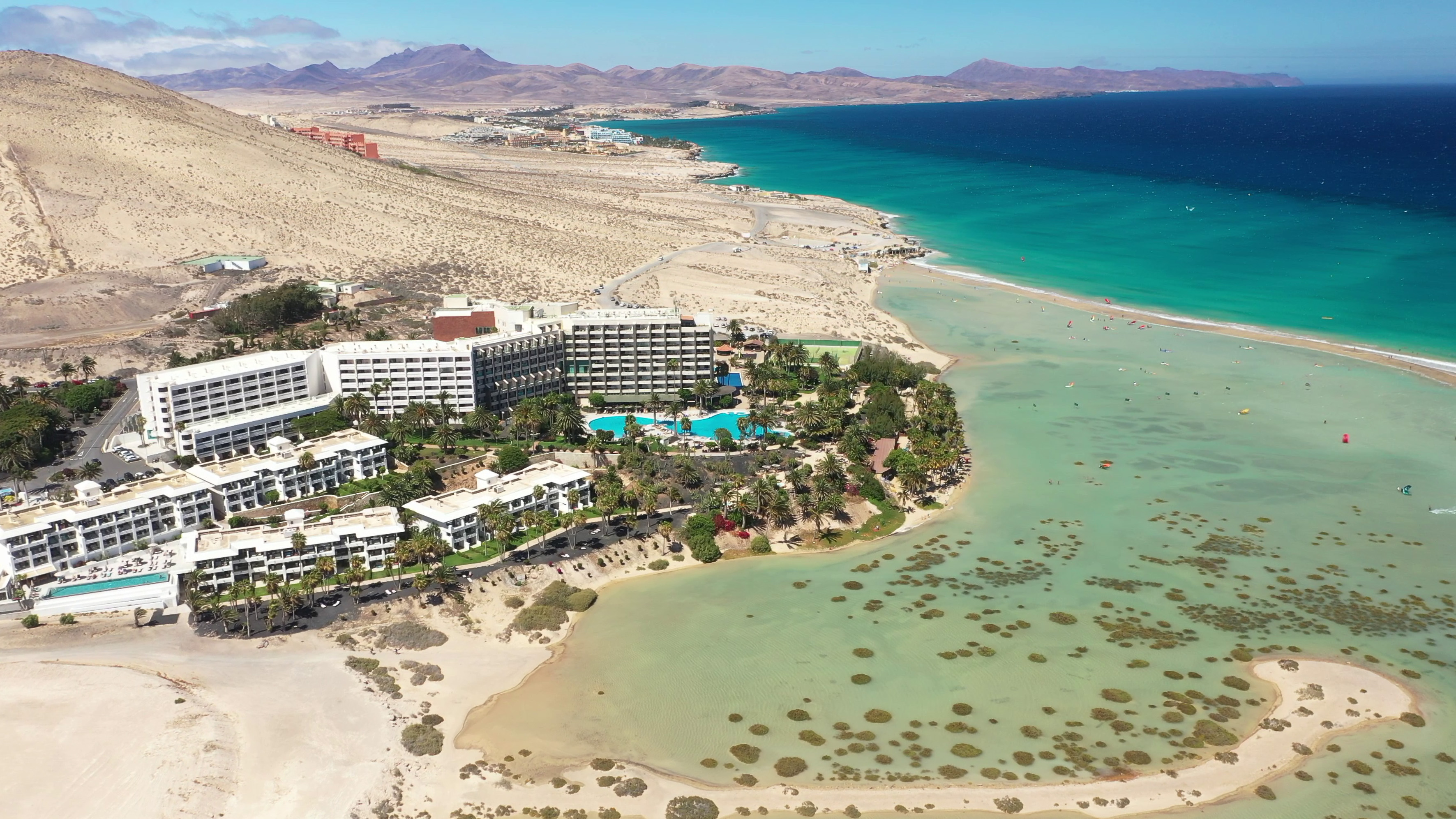 Fuerteventura resorts aerial, turquoise lagoon beach, sandy coast, desert mountains.