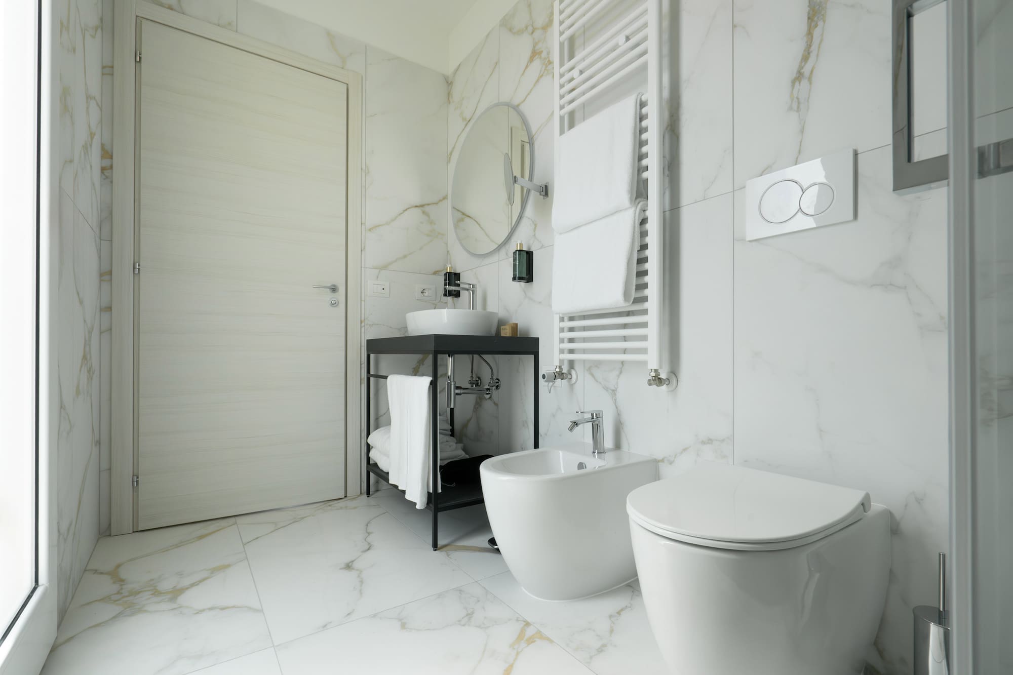 a bathroom with marble walls and a sink and toilet