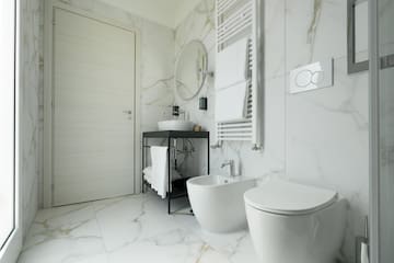 a bathroom with marble walls and a sink and toilet