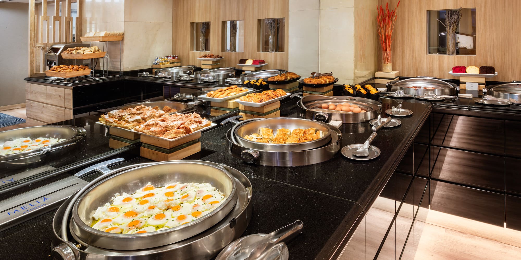 Melia Athens hotel breakfast buffet with fried eggs, pastries, and hot dishes.