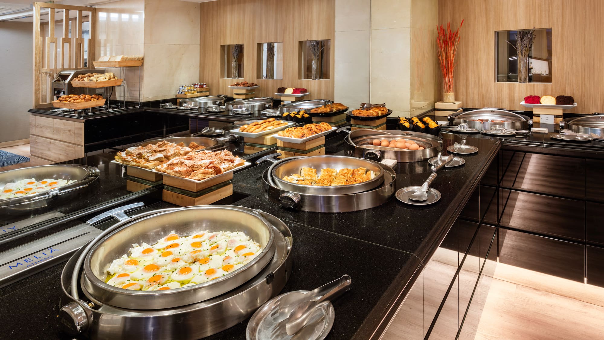 Melia Athens hotel breakfast buffet with fried eggs, pastries, and hot dishes.