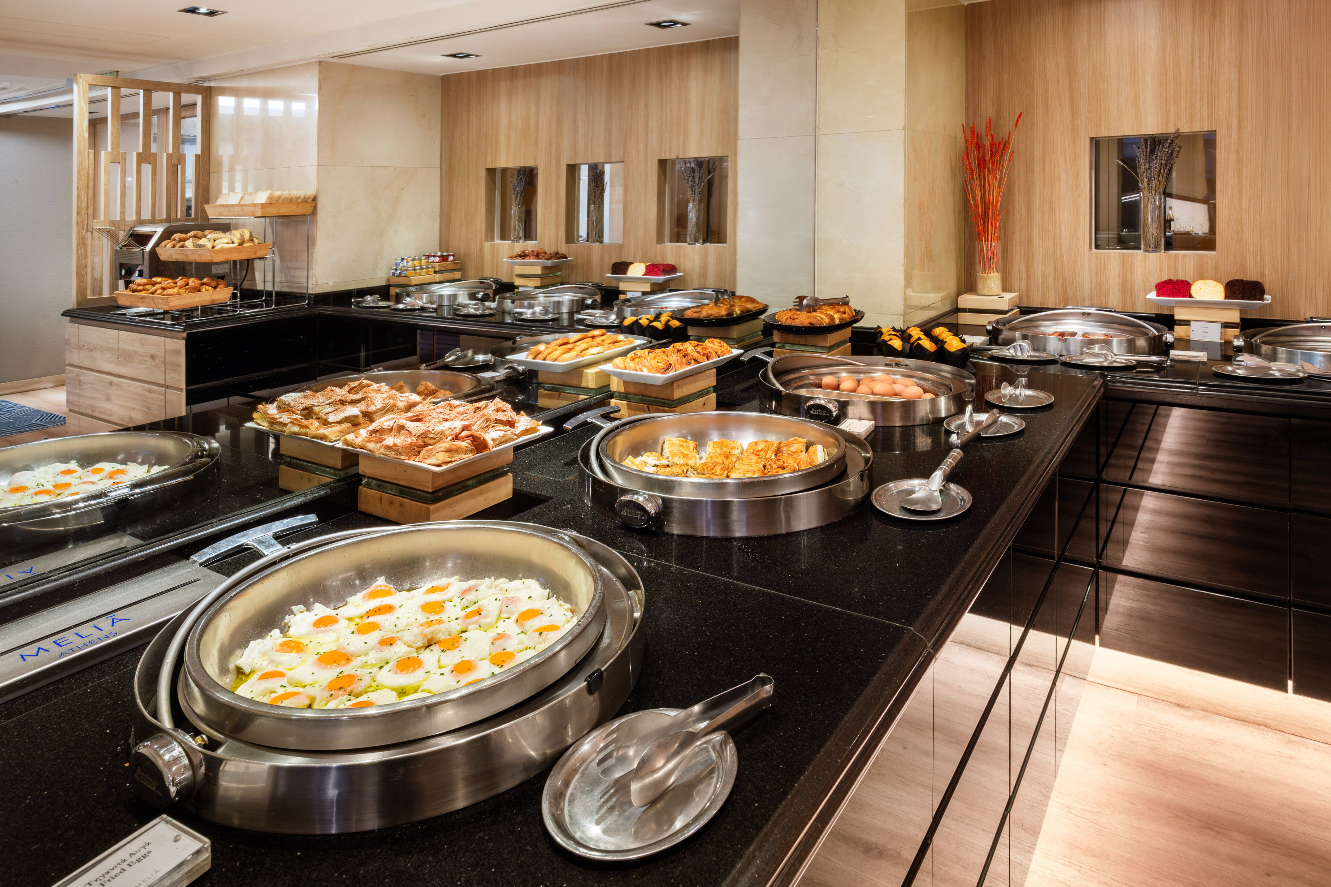 Melia Athens hotel breakfast buffet with fried eggs, pastries, and hot dishes.