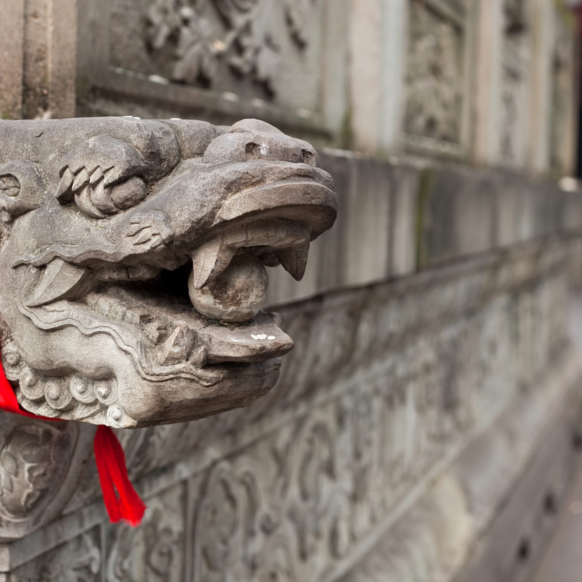 a stone dragon head with a red ribbon
