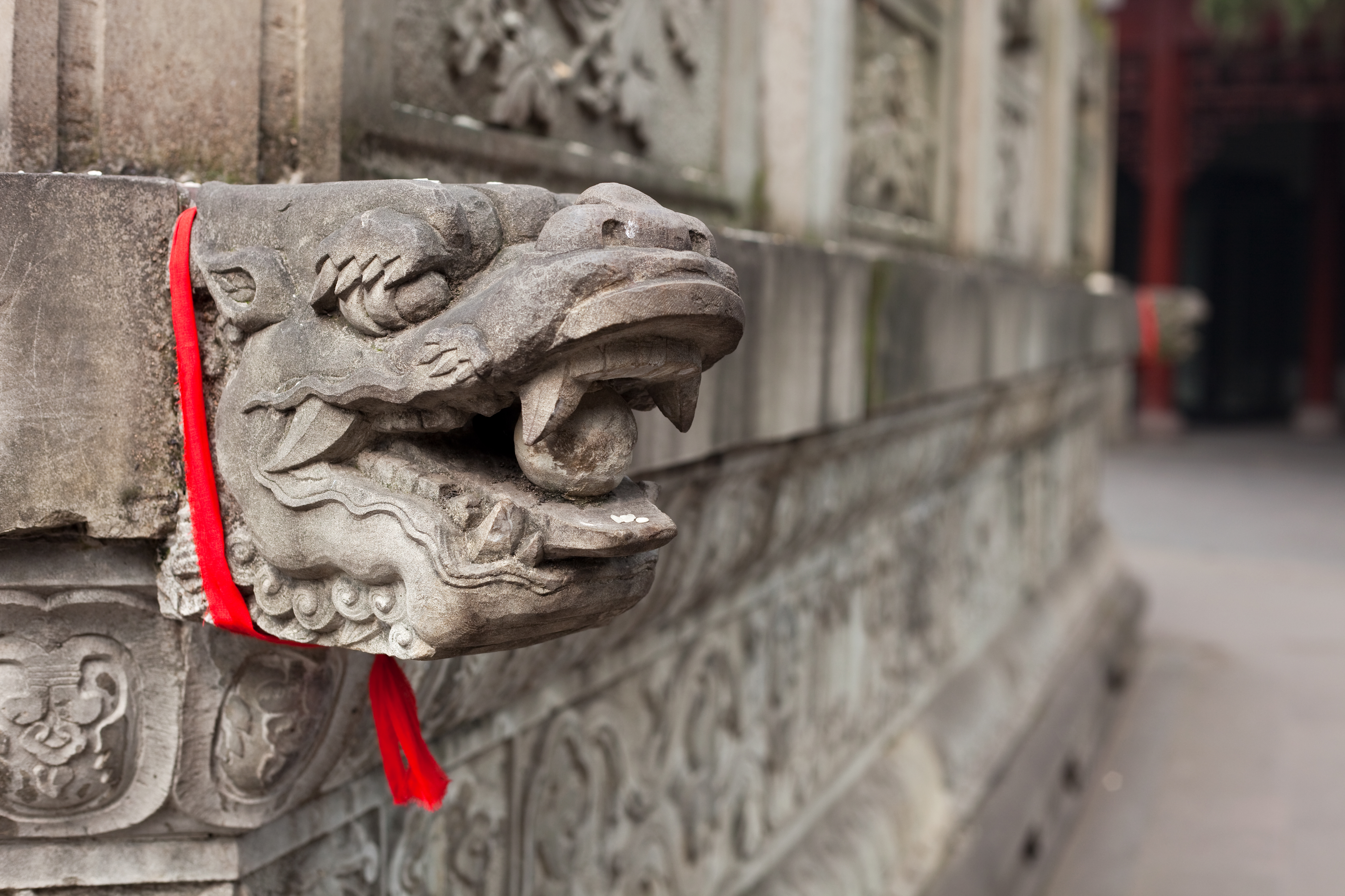 a stone dragon head with a red ribbon