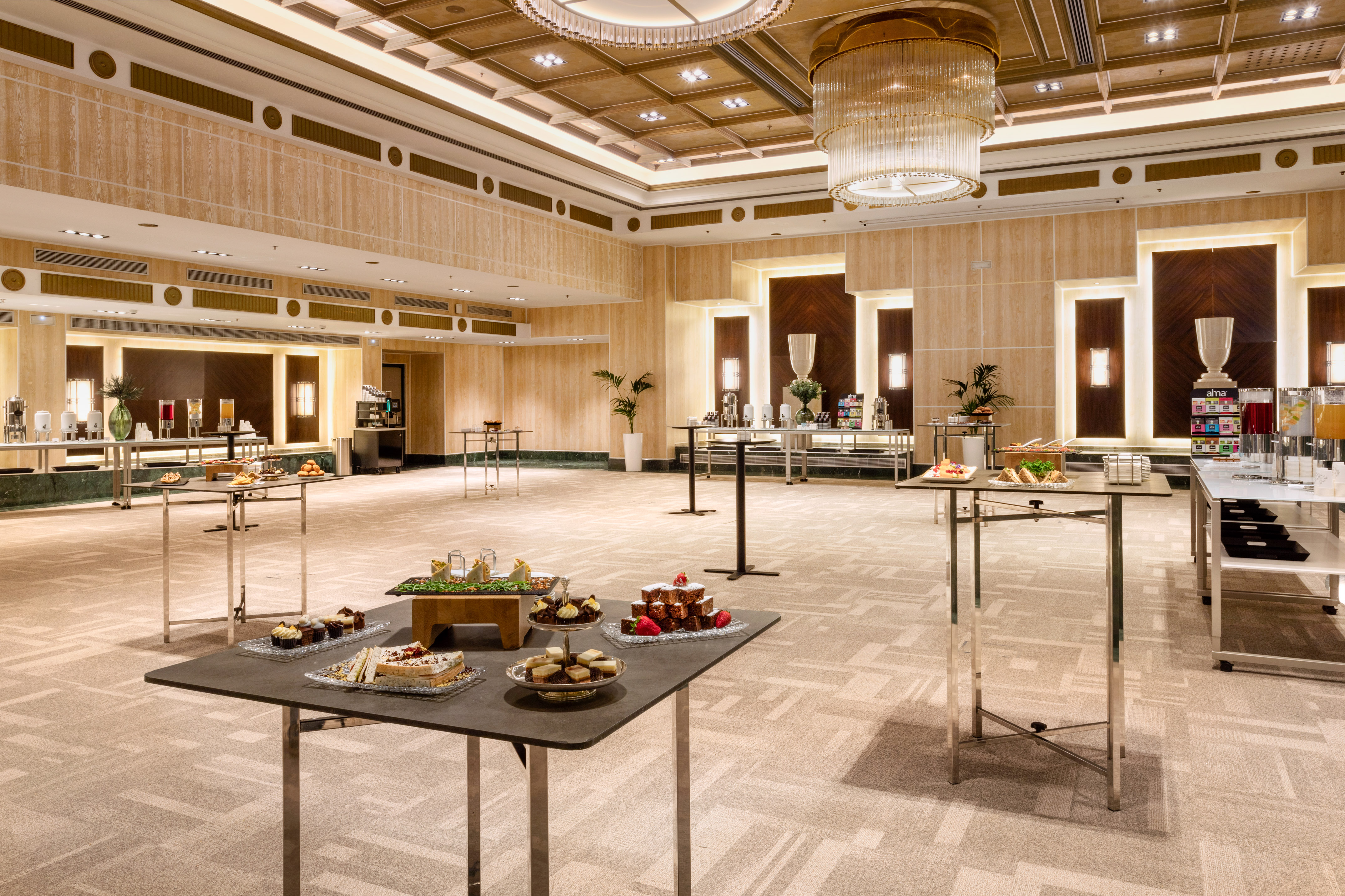 Elegant ballroom with buffet catering: assorted desserts, sandwiches, and beverages.