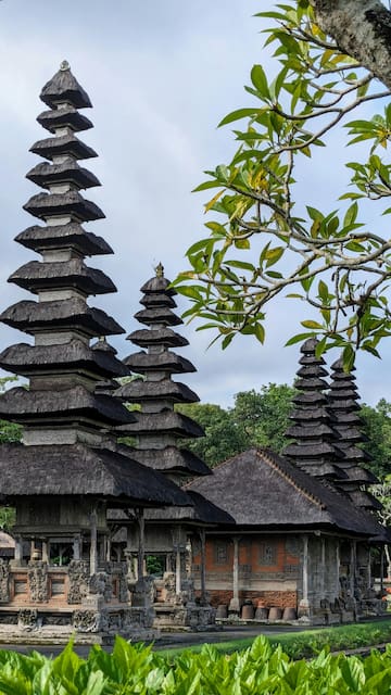 a group of wooden buildings with a tree in the background with Small Wild Goose Pagoda in the background