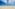 a sandy beach with blue water and clouds in the sky