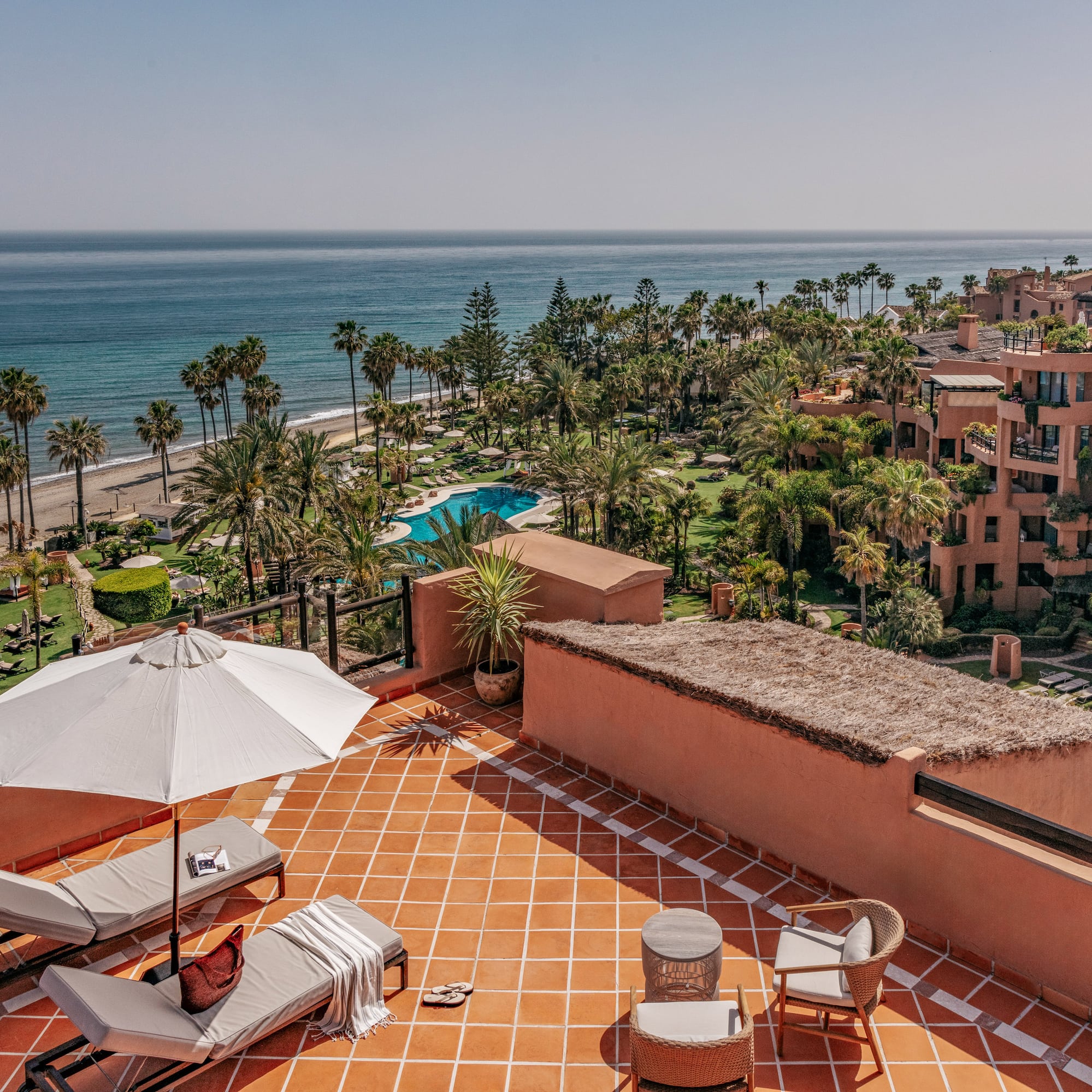 Rooftop terrace with ocean, beach, palm trees, and luxury resort view.
