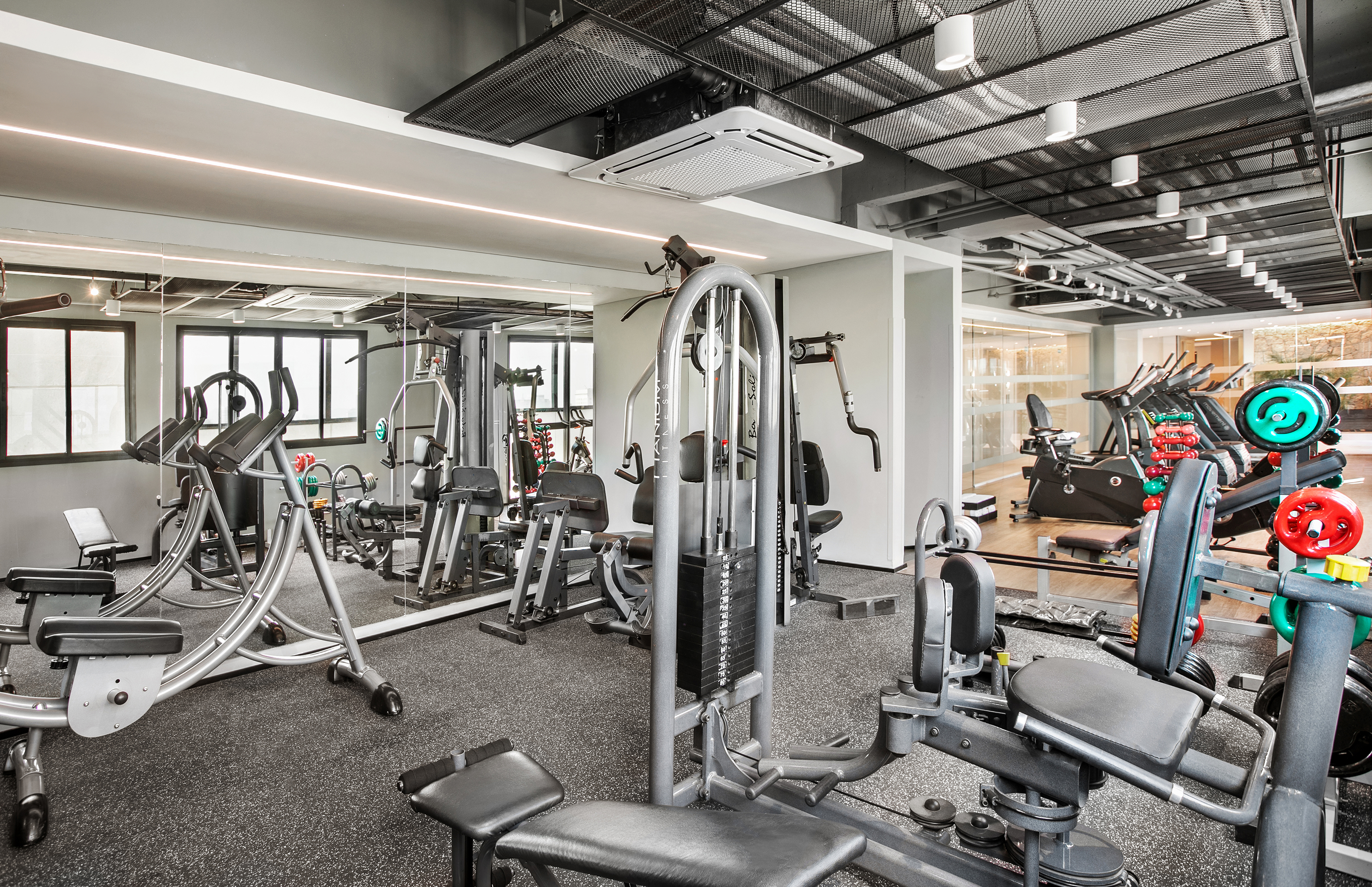 Well-equipped modern gym with weight machines, cardio, and mirrored walls.