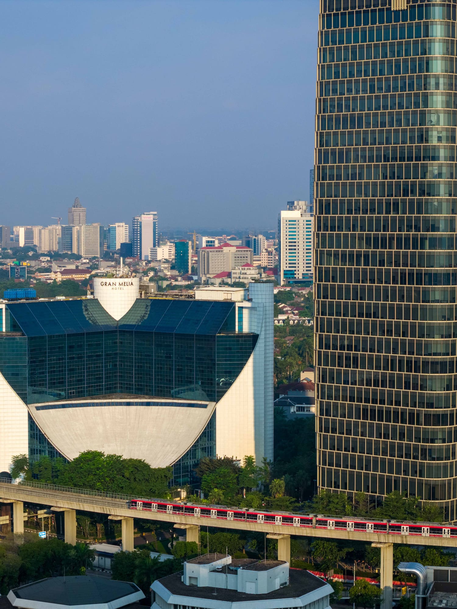 Modern Jakarta cityscape with Gran Melia Hotel and elevated red train.