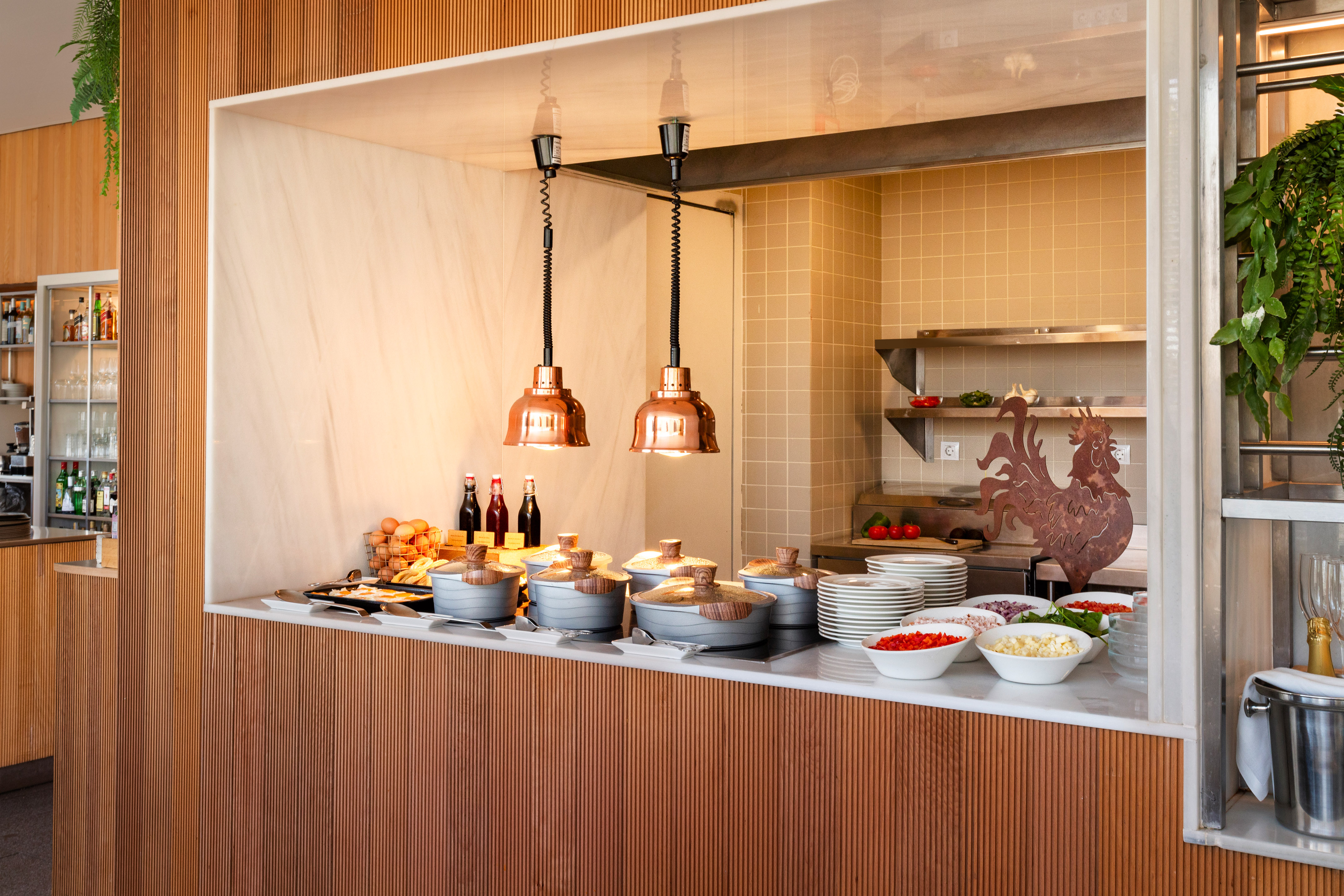 Hotel buffet serving station with warm food, fresh ingredients, and copper lamps.