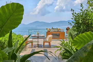 a table and chairs on a patio overlooking a body of water